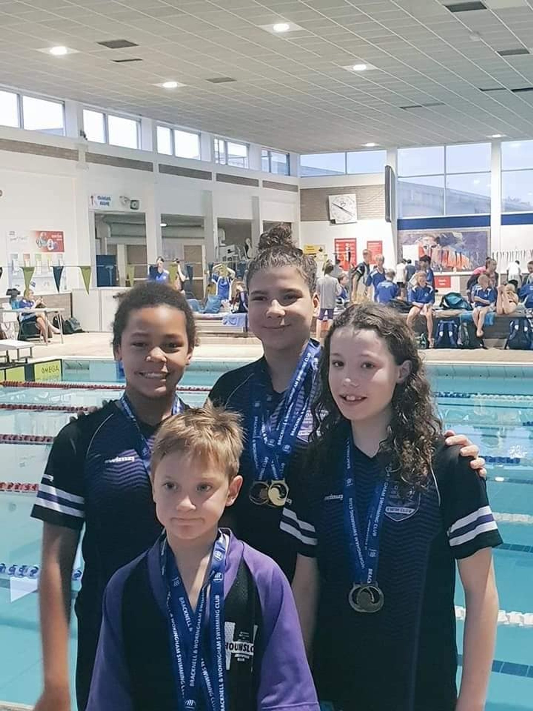 LBHSC swimmers with their medals beside the competition pool