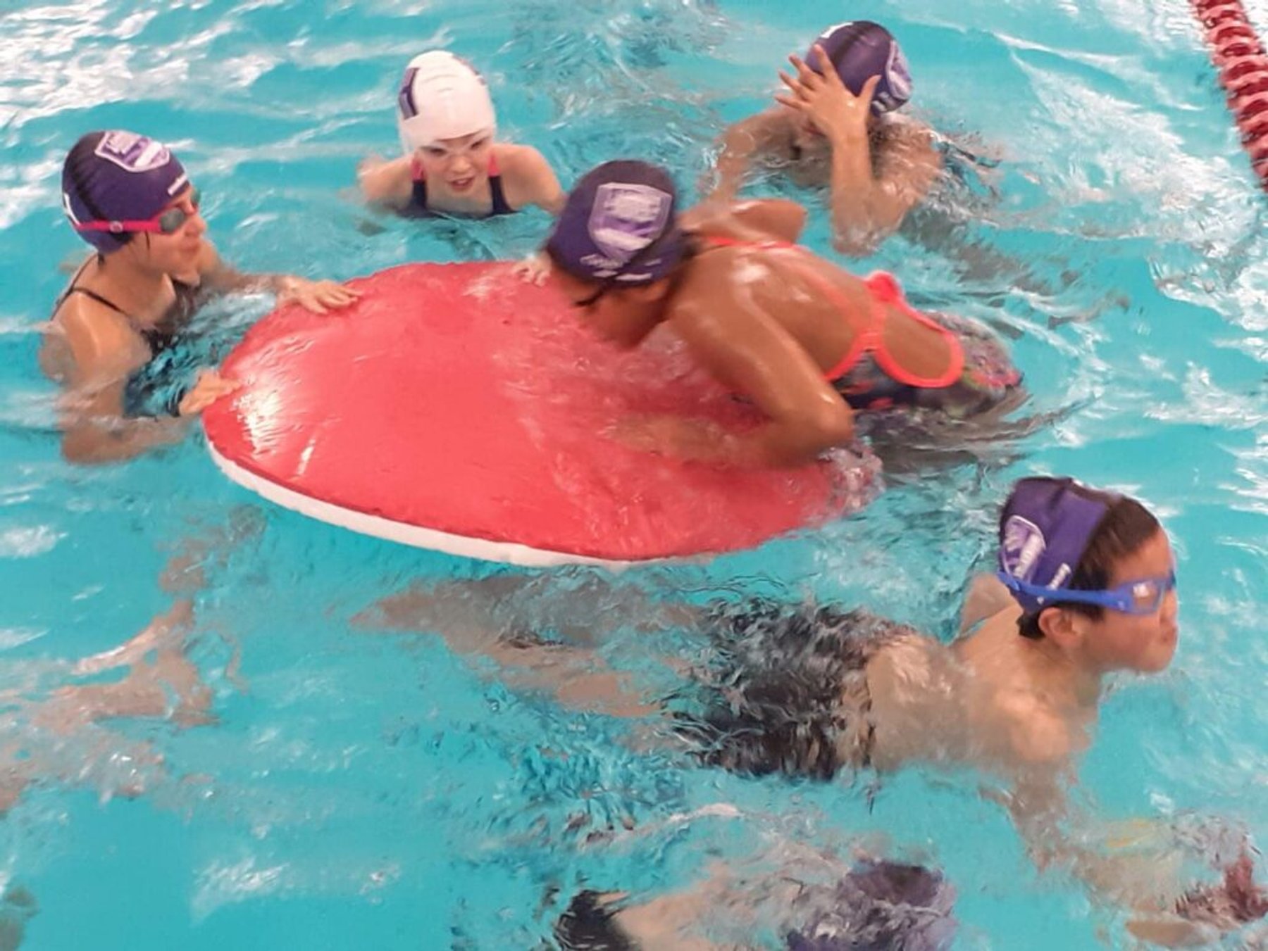 Young swimmers playing on a large float during a lesson