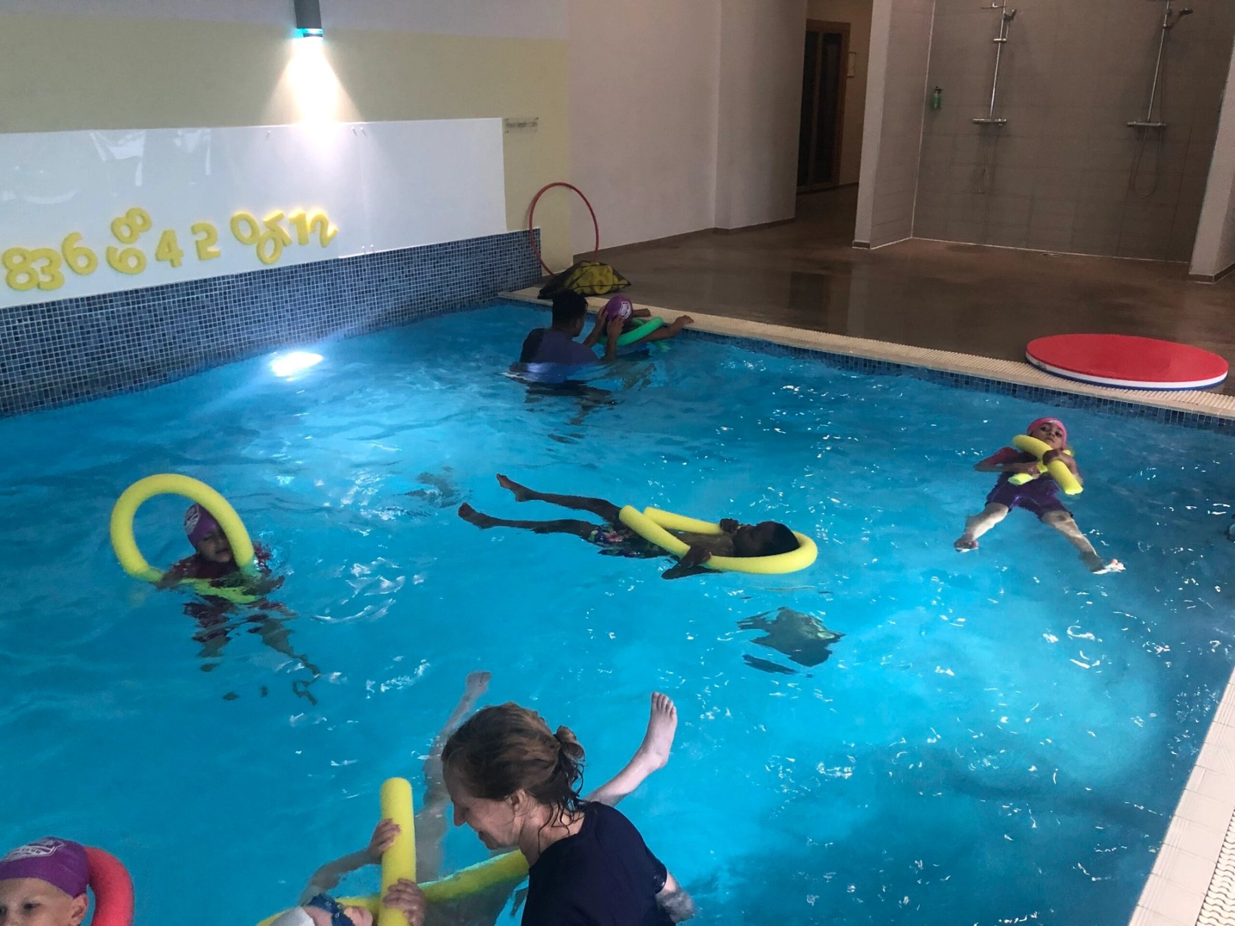 Swimmers with floats spread across the pool in a community session