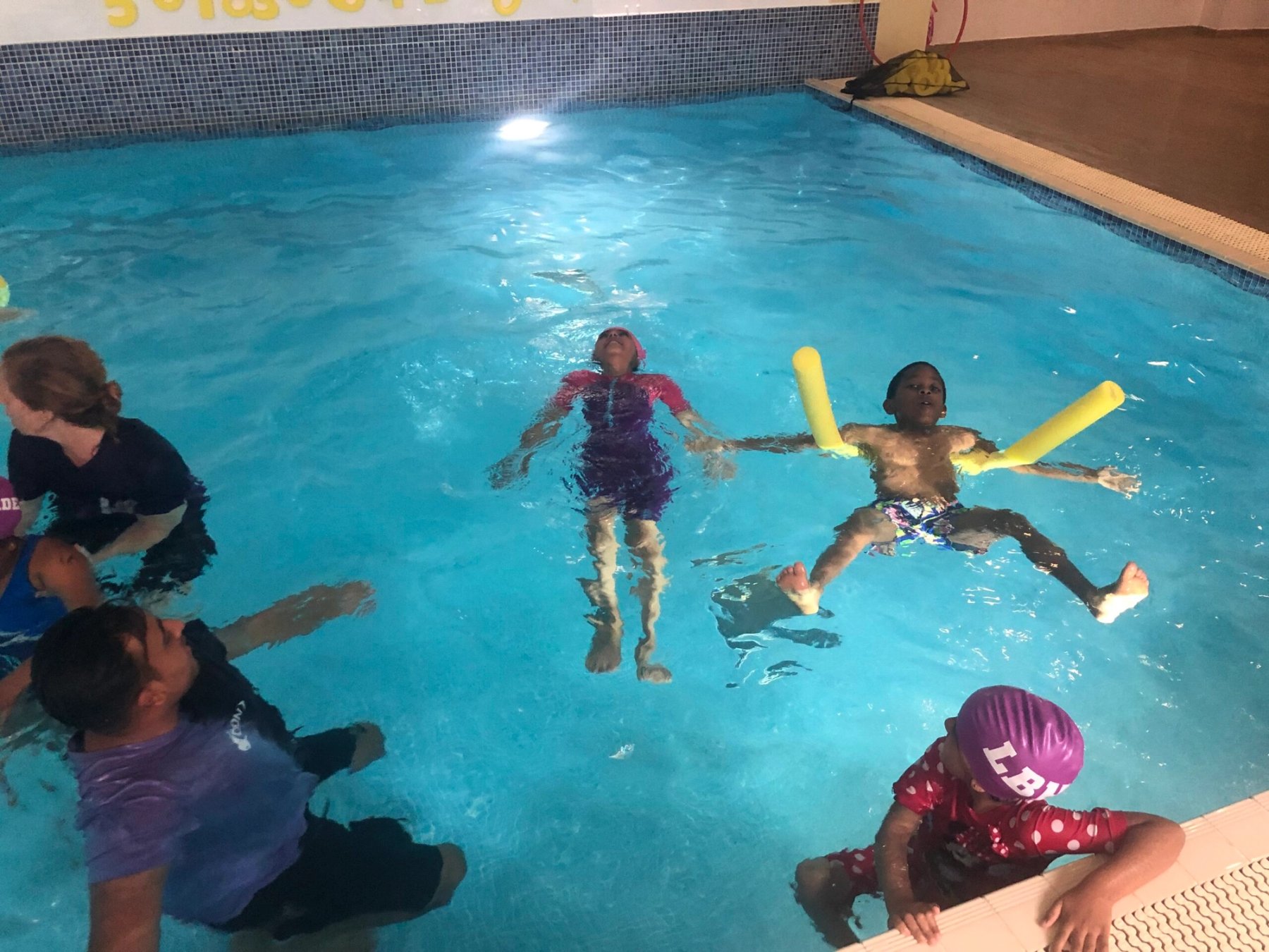 A swimmer practising floating with noodles during a community session