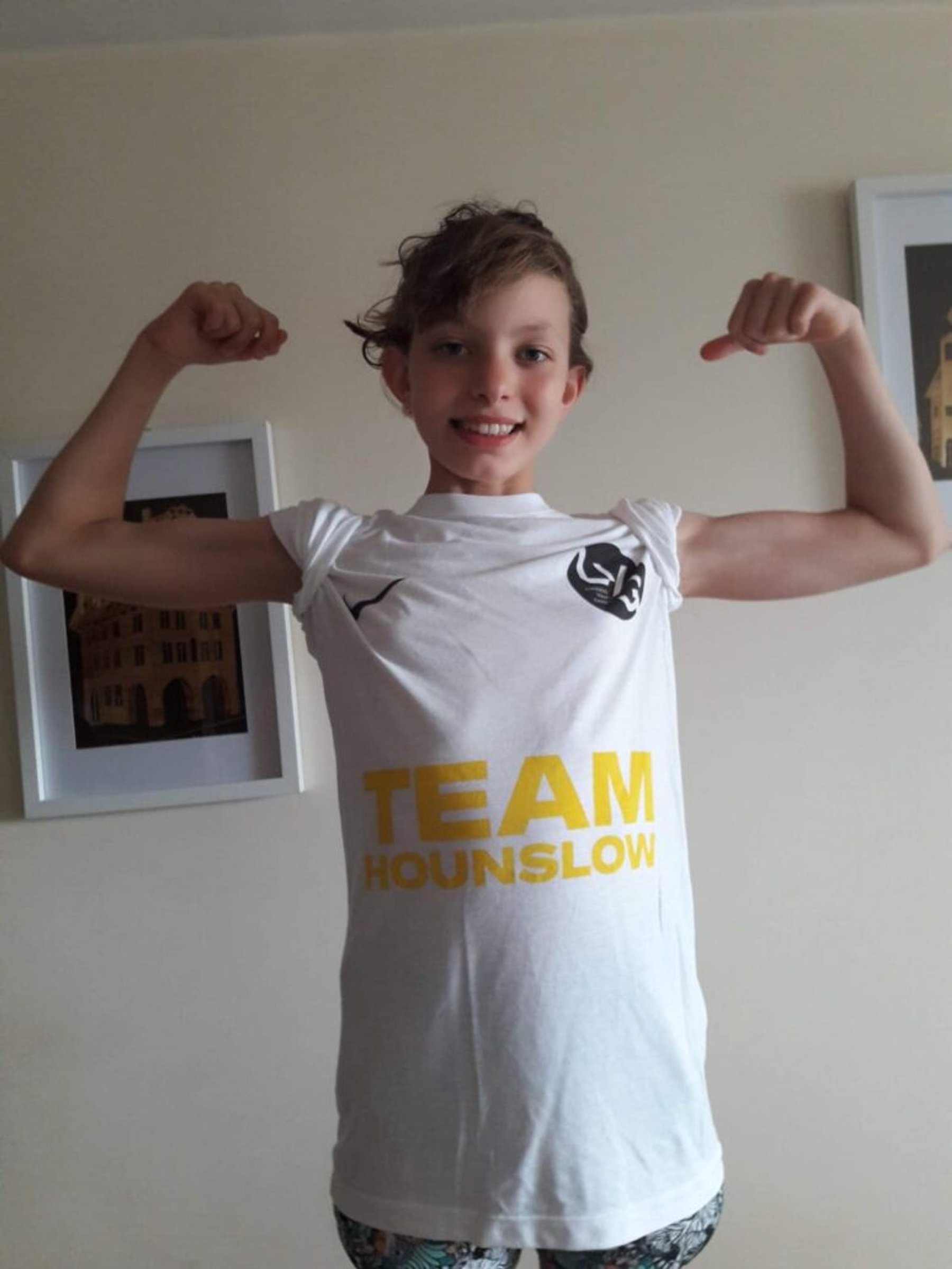An LBHSC swimmer in a Team Hounslow t-shirt flexing for the camera
