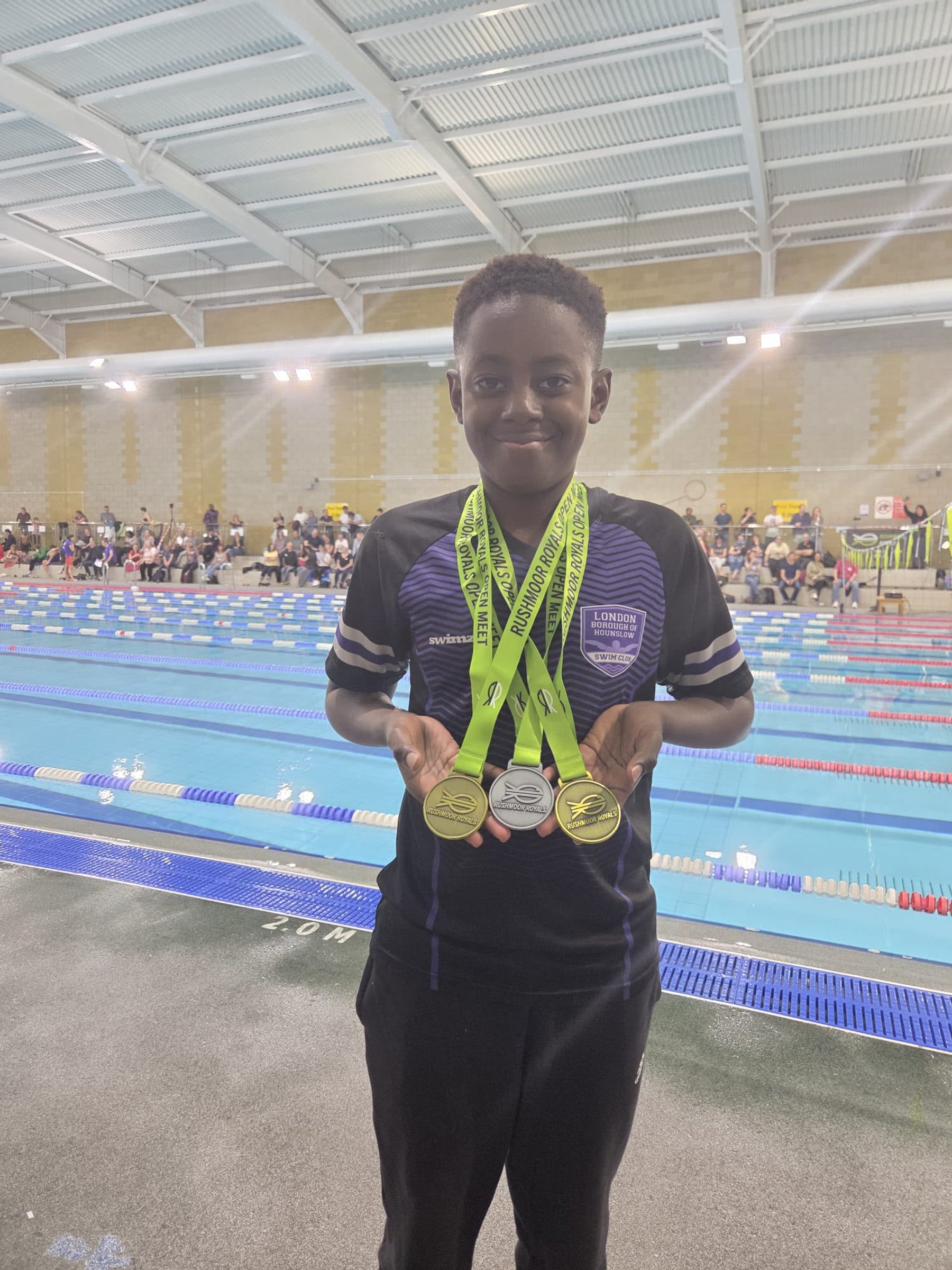 LBHSC swimmer holding his medals at a gala