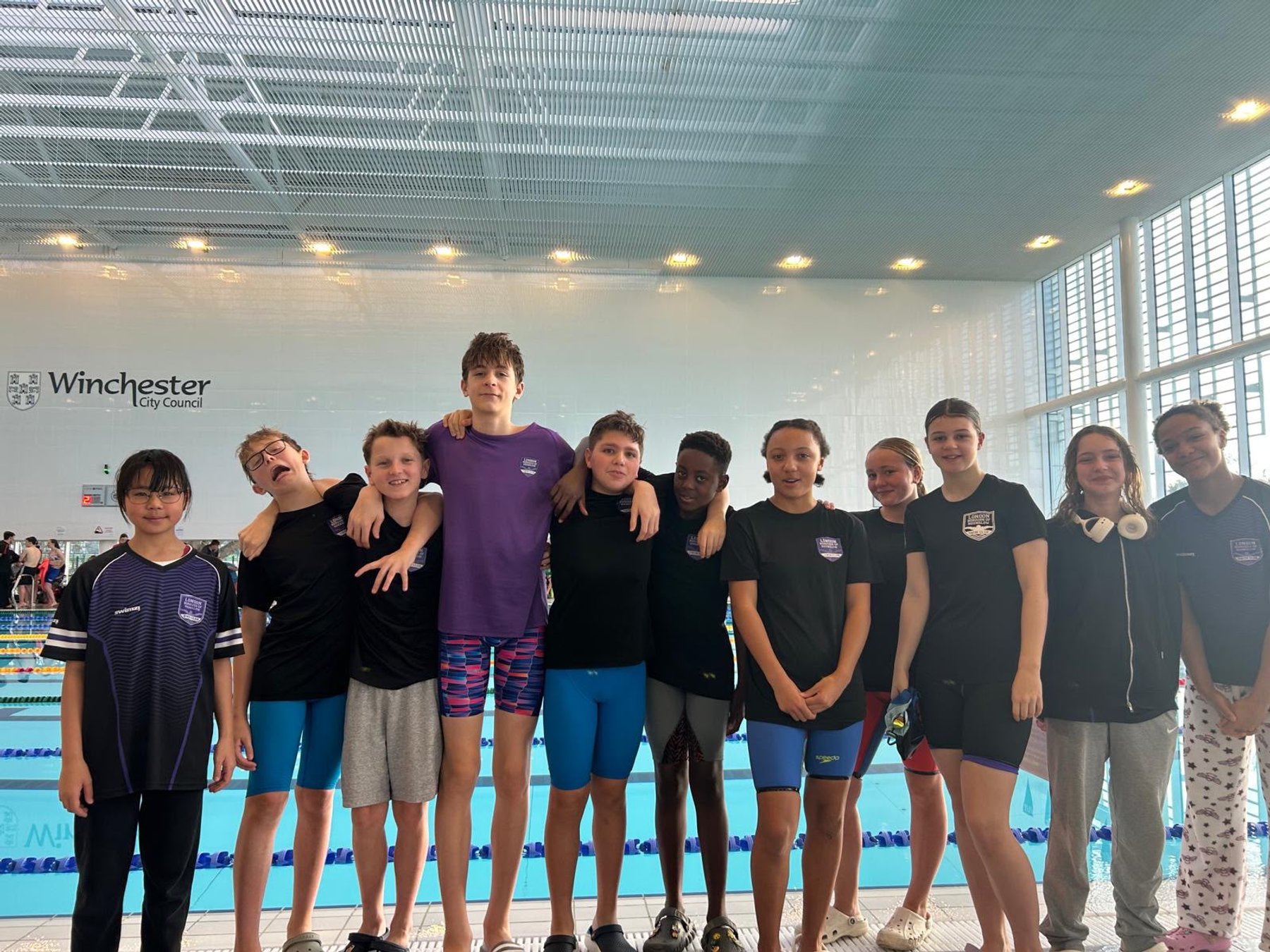 Swim team gathered for a group photo beside the pool.