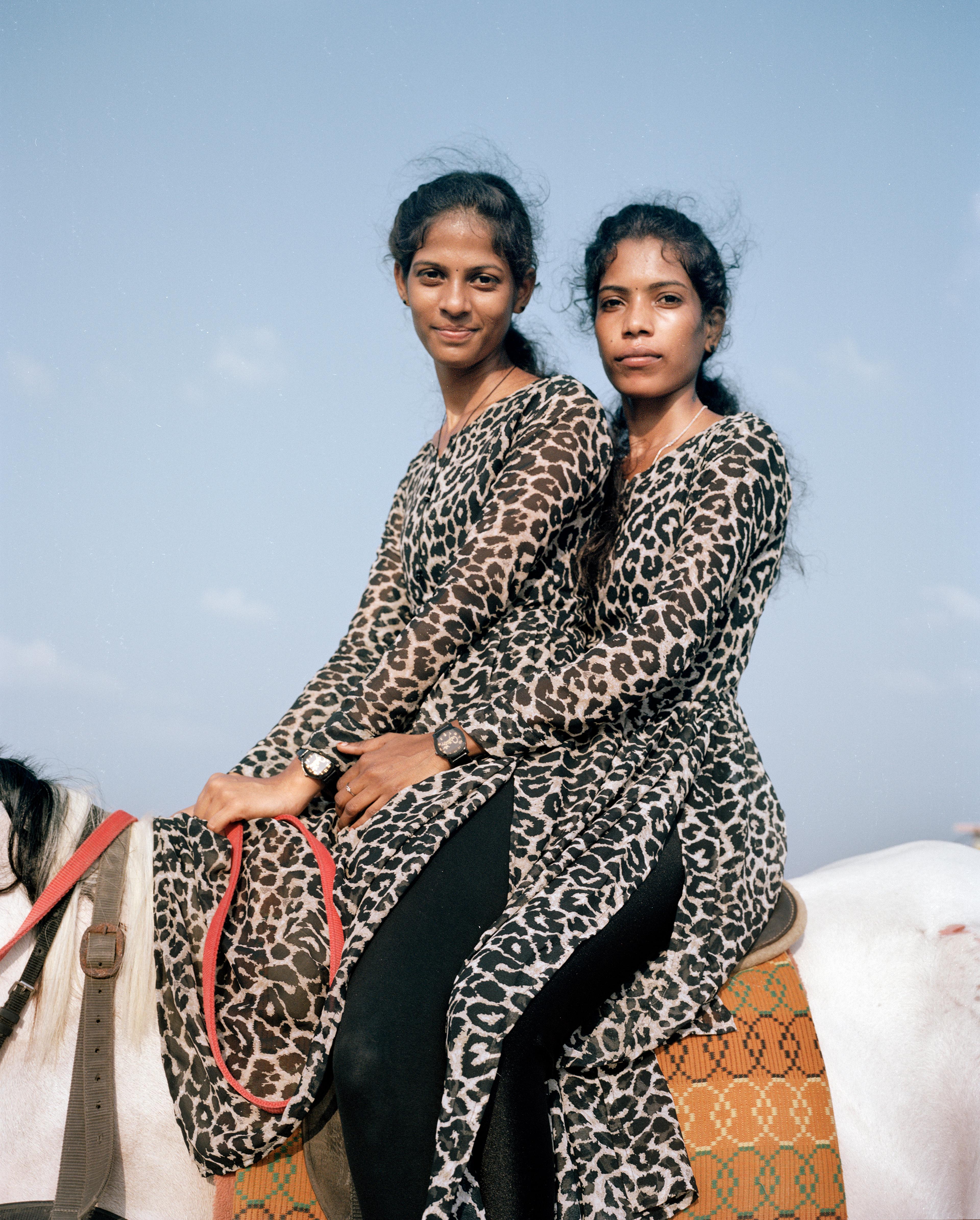 Two young girls sitting on the back of a horse