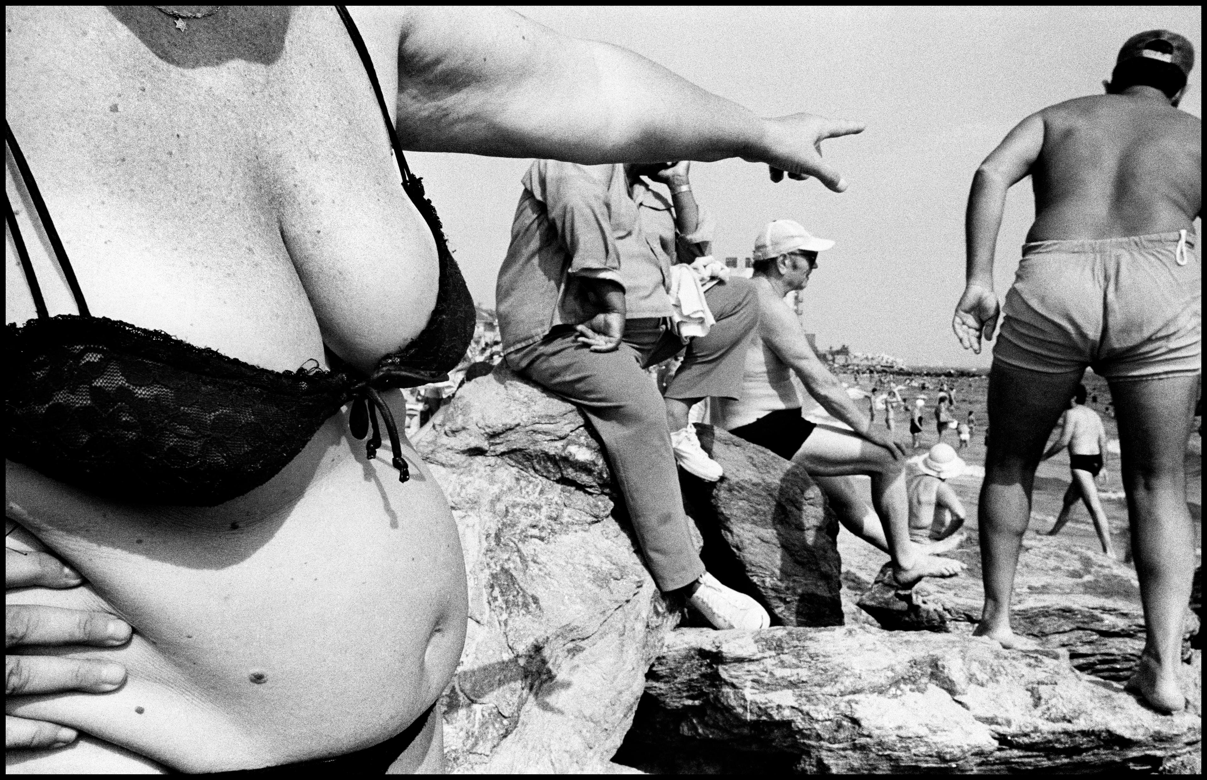 A black-and-white candid photograph of a group of people in bathing suits at Coney Island