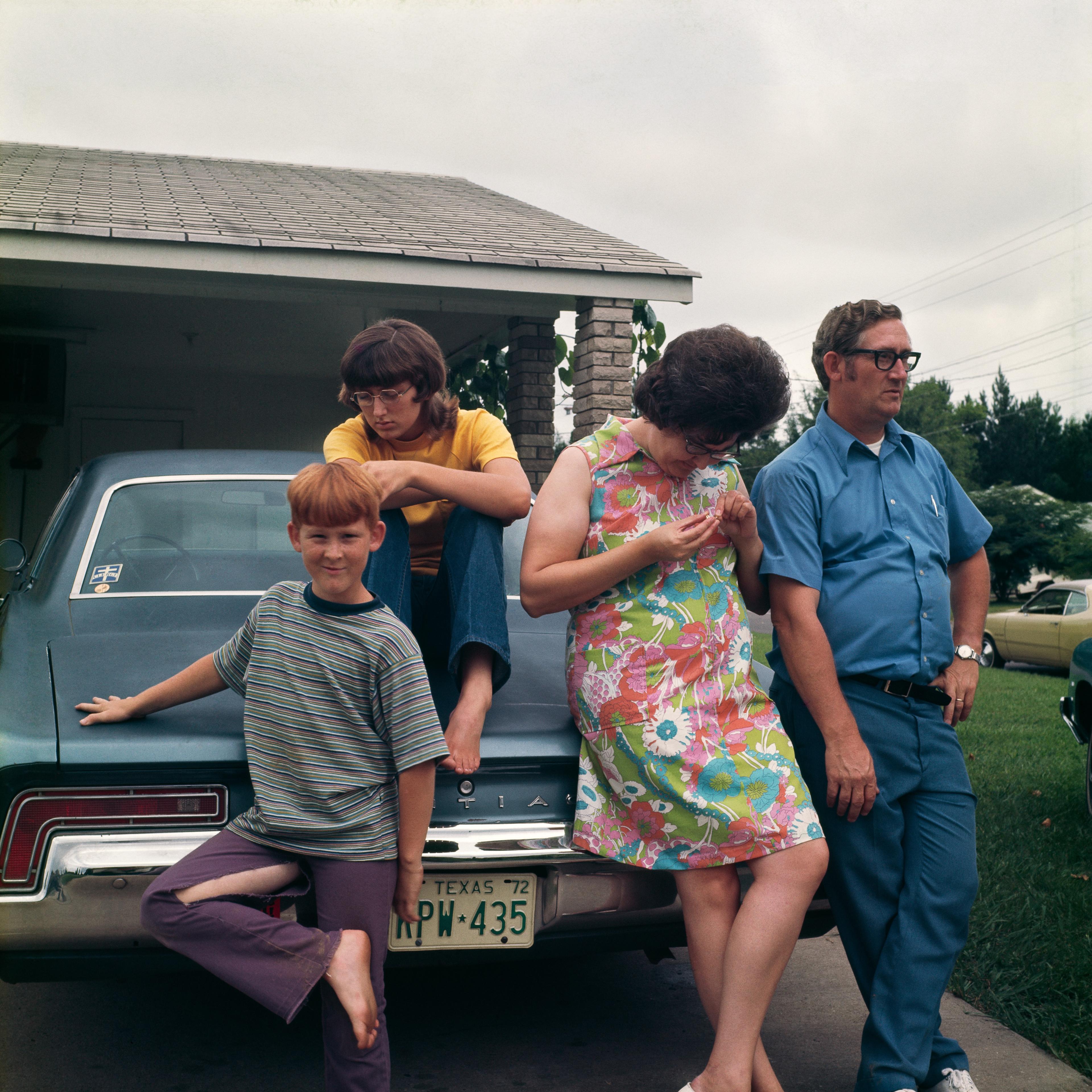 Photograph of a of an American family in the 1970s behind their car