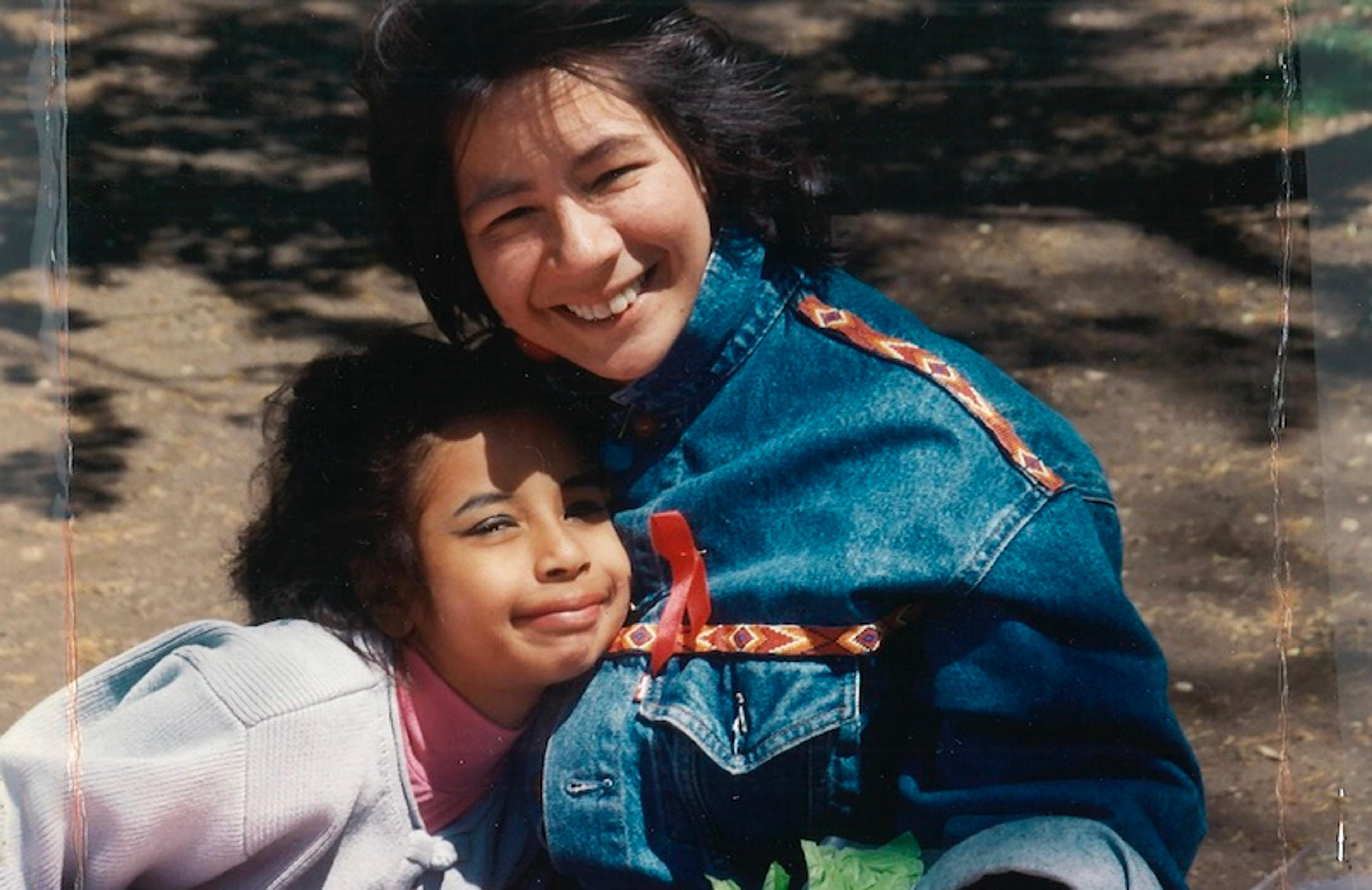 A photograph of a child hugging an adult wearing a denim jacket