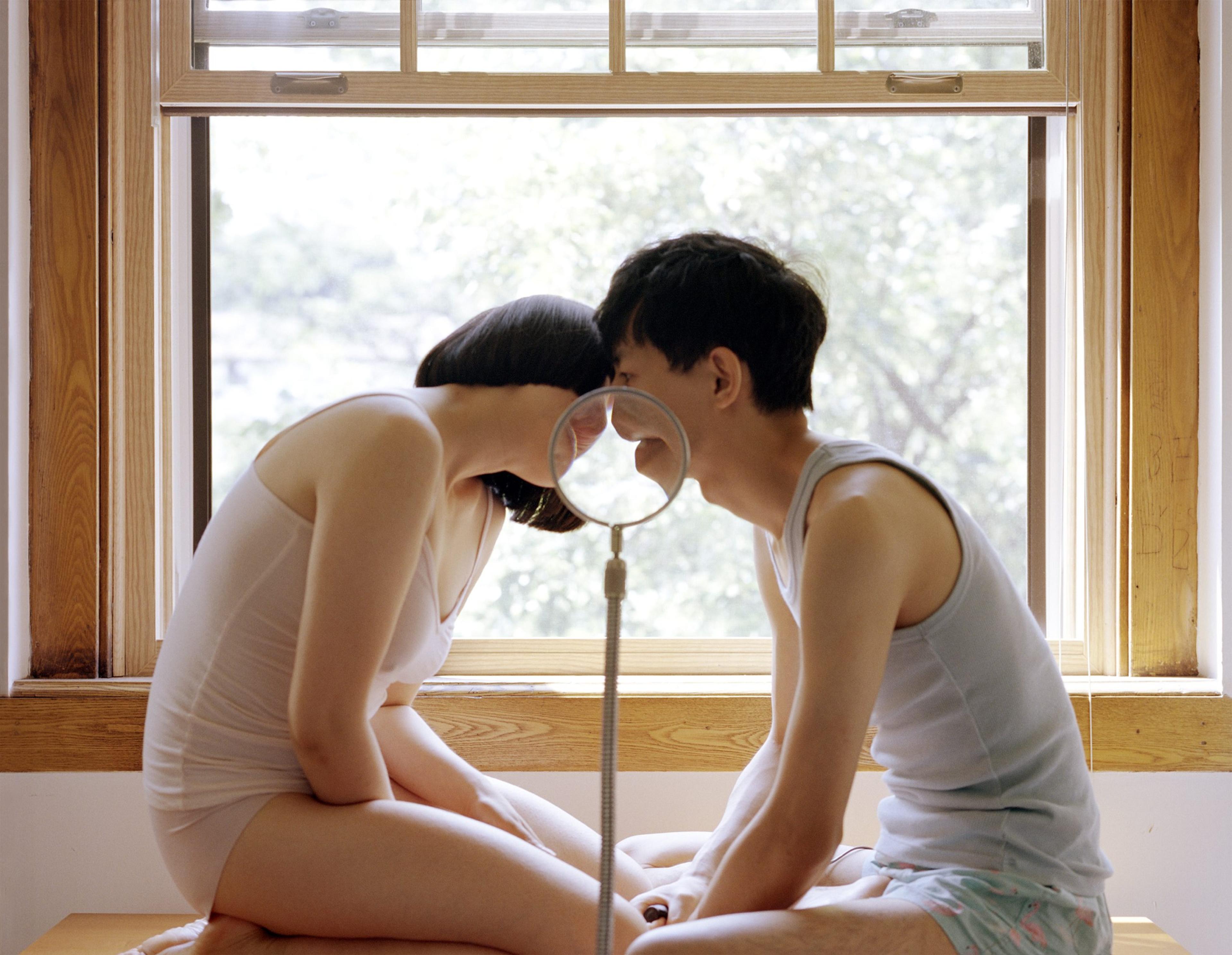 An image of a couple in pajamas kissing behind a magnifying glass