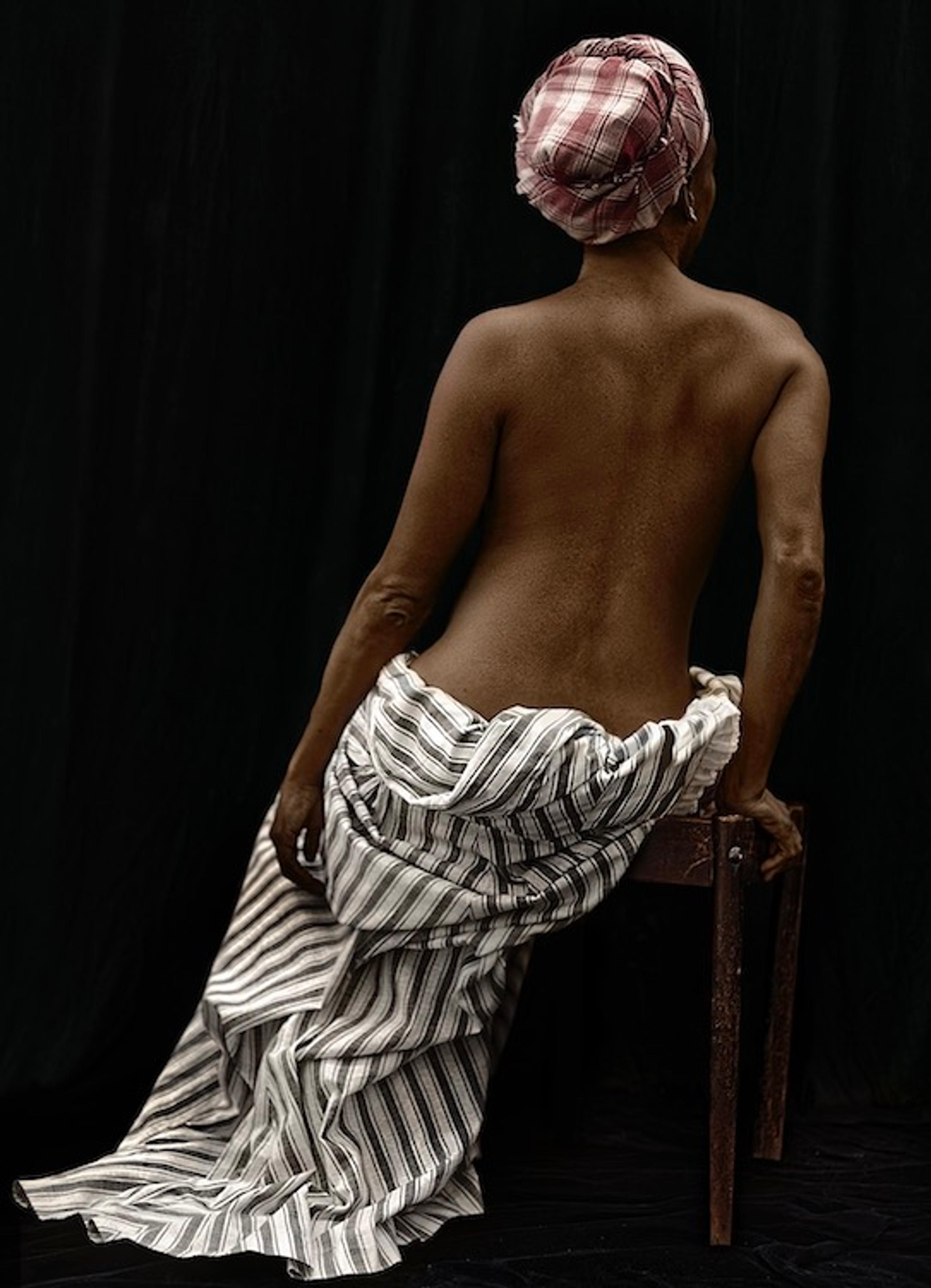 A portrait taken from the back of an unclothed woman wearing a head covering