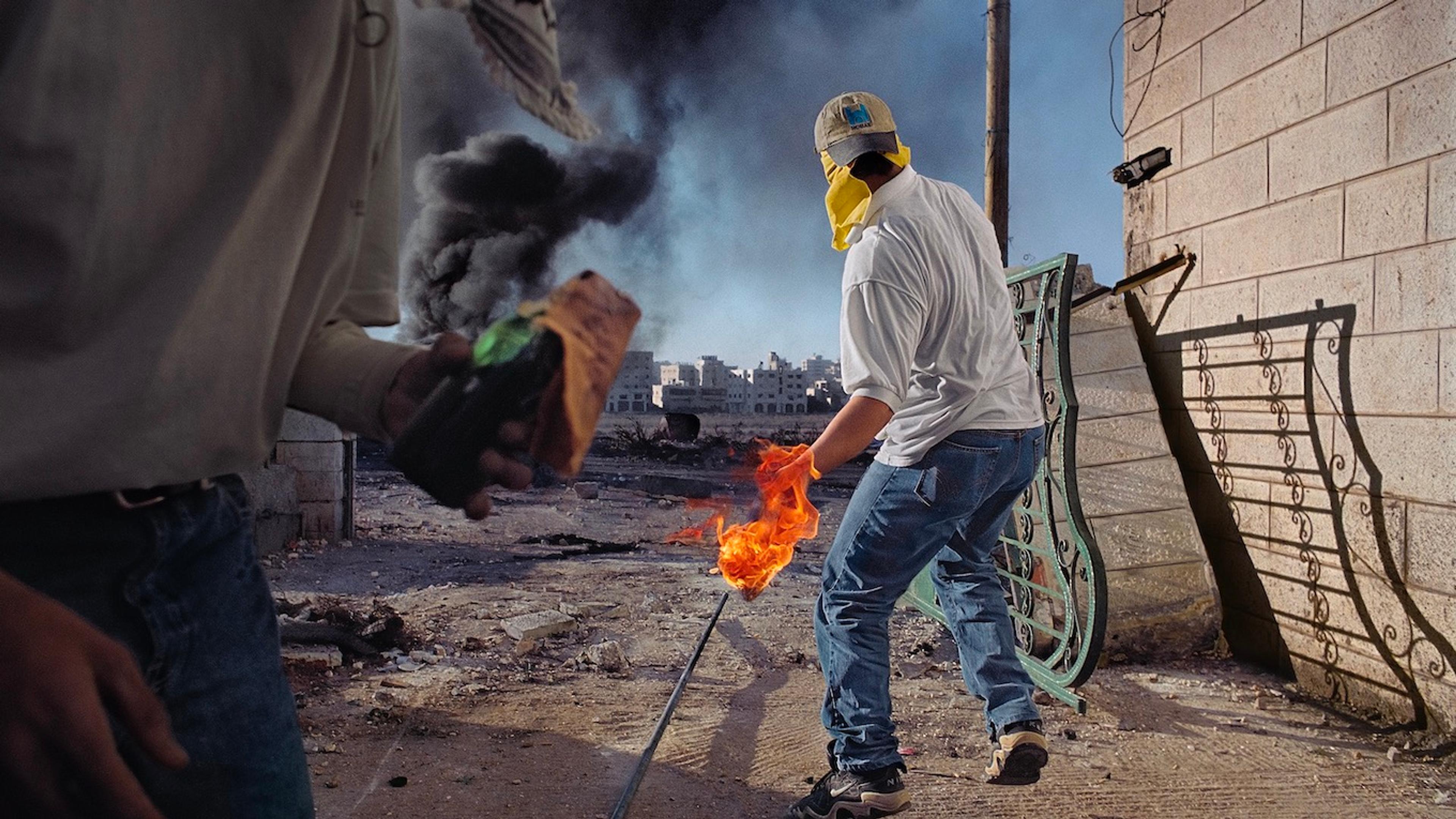 A photographic artwork featuring fire, smoke, and a man in jeans and a white tee shirt