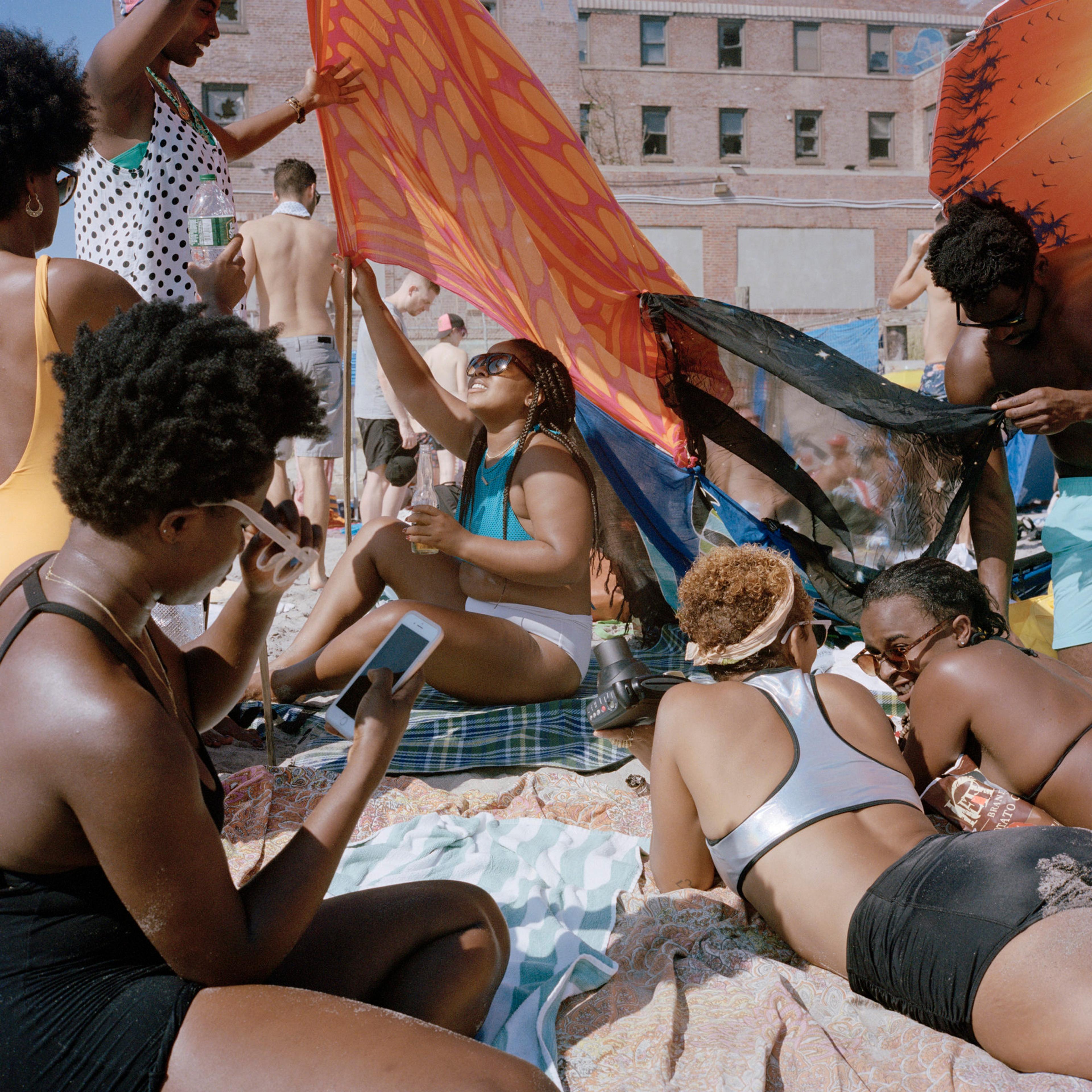 A photograph of a group of women lounging on the beach and conversing