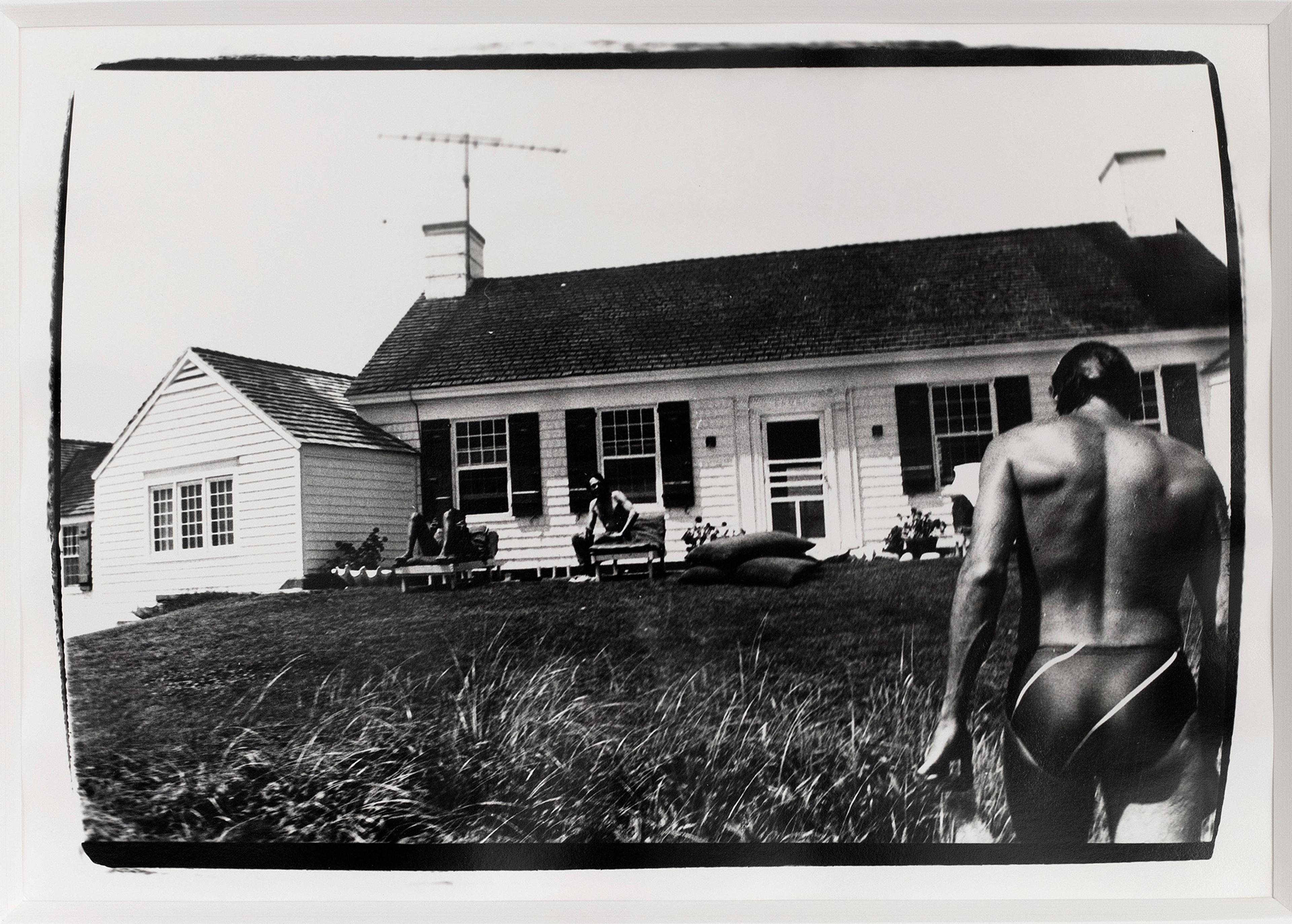  Schwarz-weißes Foto eines Mannes, der auf ein weißes Haus zugeht.