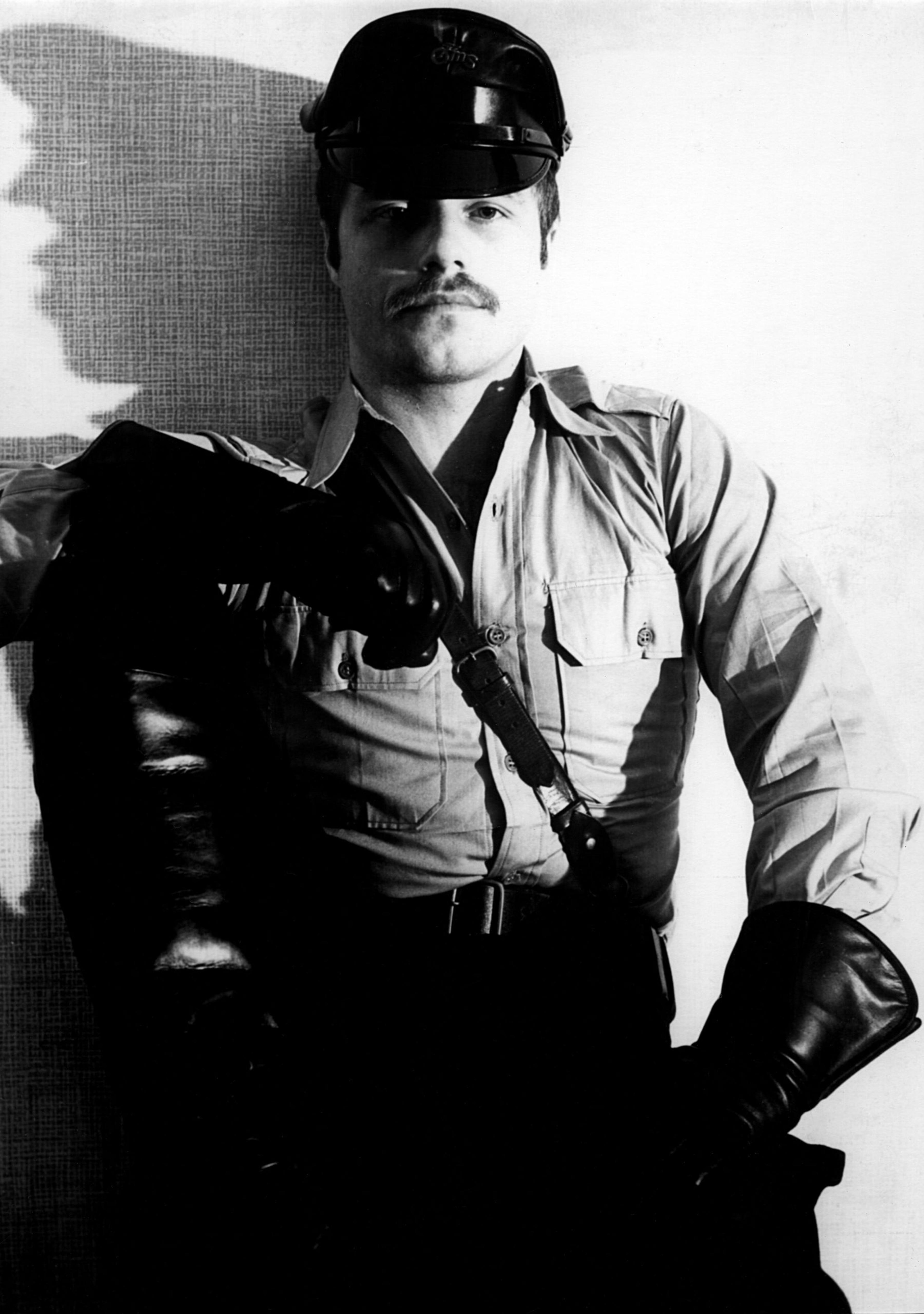 A black and white portrait of a man in uniform wearing black leather gloves