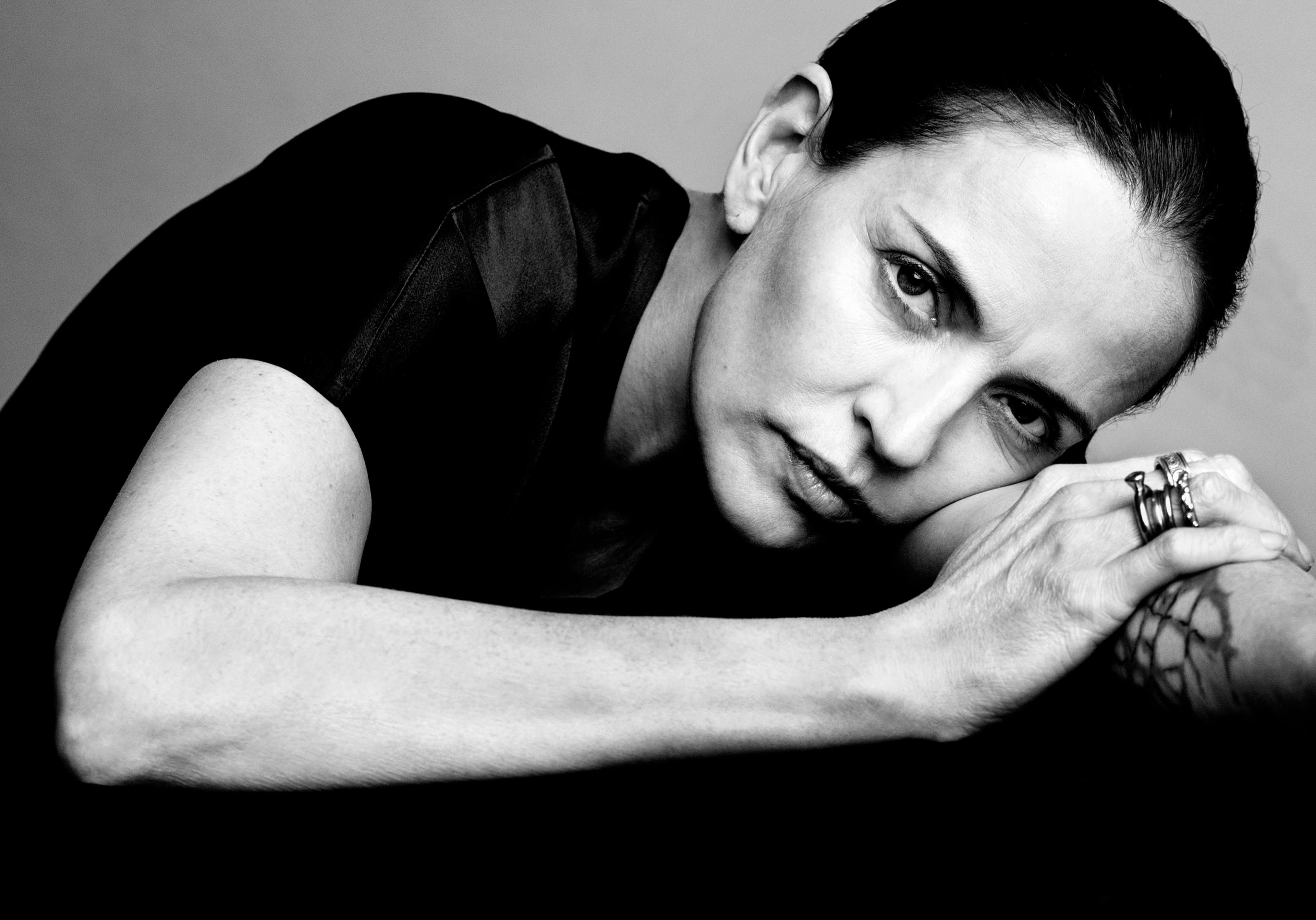 Portrait of a woman resting her head on her arms, looking directly into the camera.