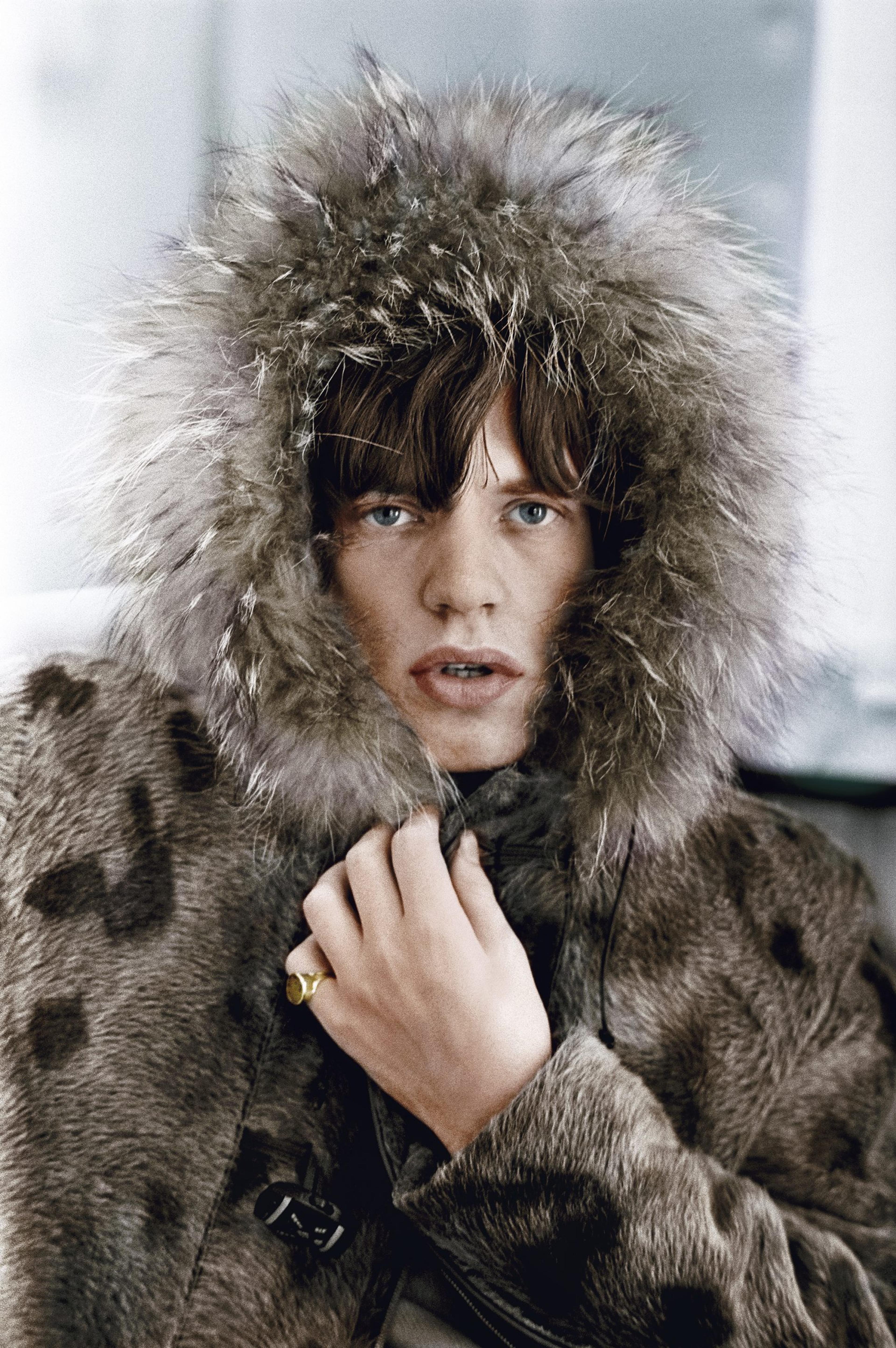 A portrait of Mick Jagger in a brown spotted fur coat wearing a gold pinky ring