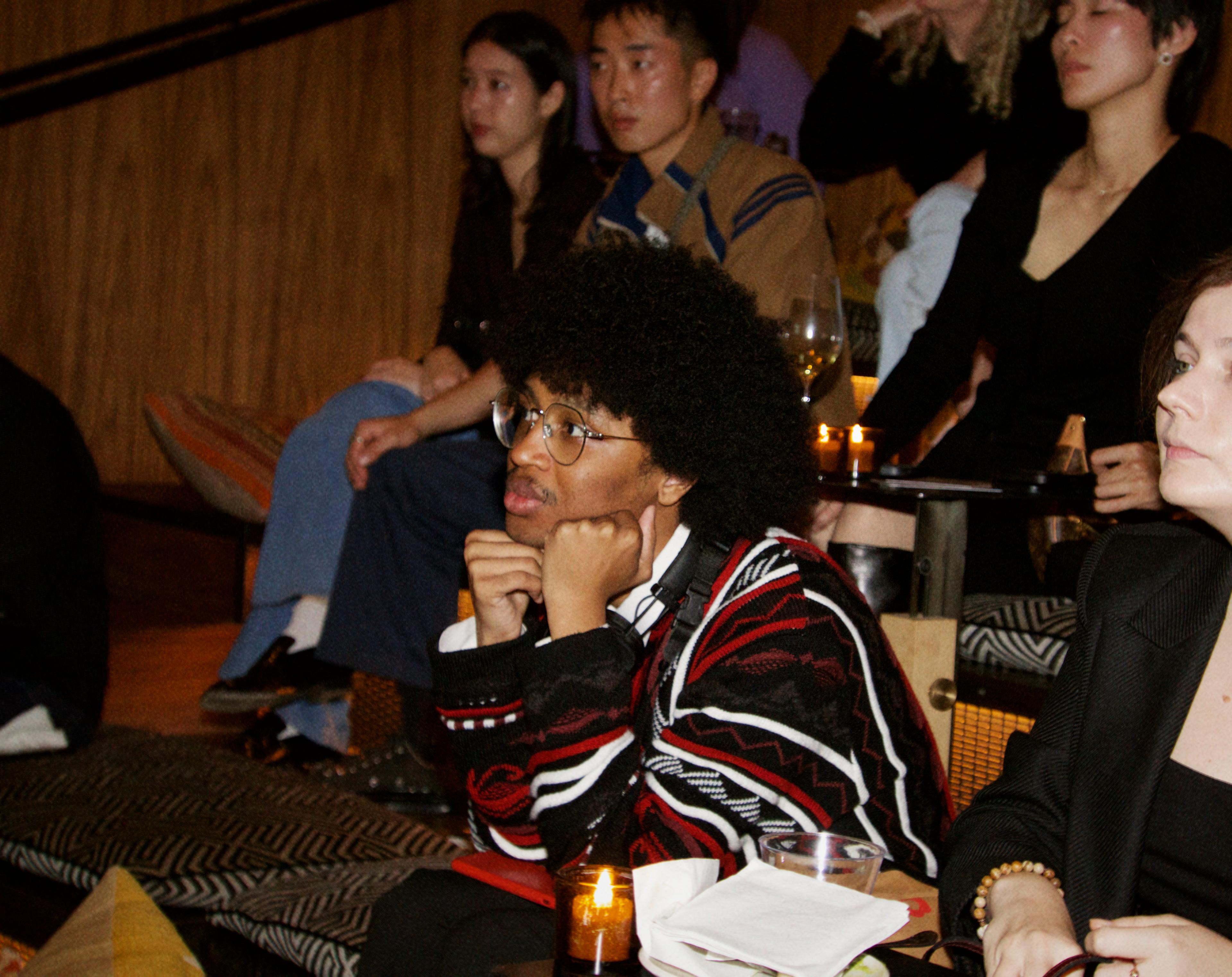 A guest listens intently with their face resting on their fists