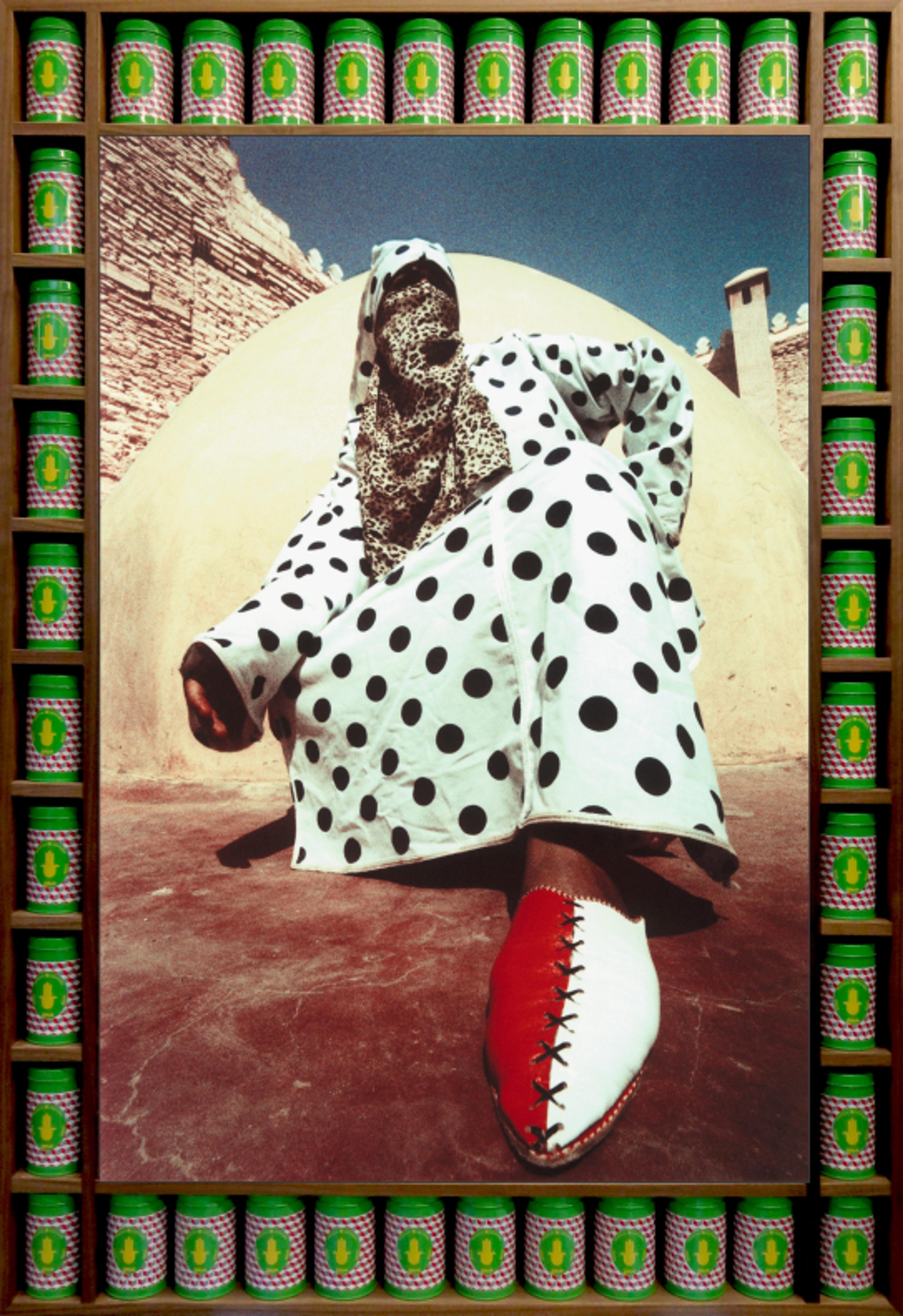 A photograph of a person wearing a polka-dot djellaba and hijab posing in a squat position