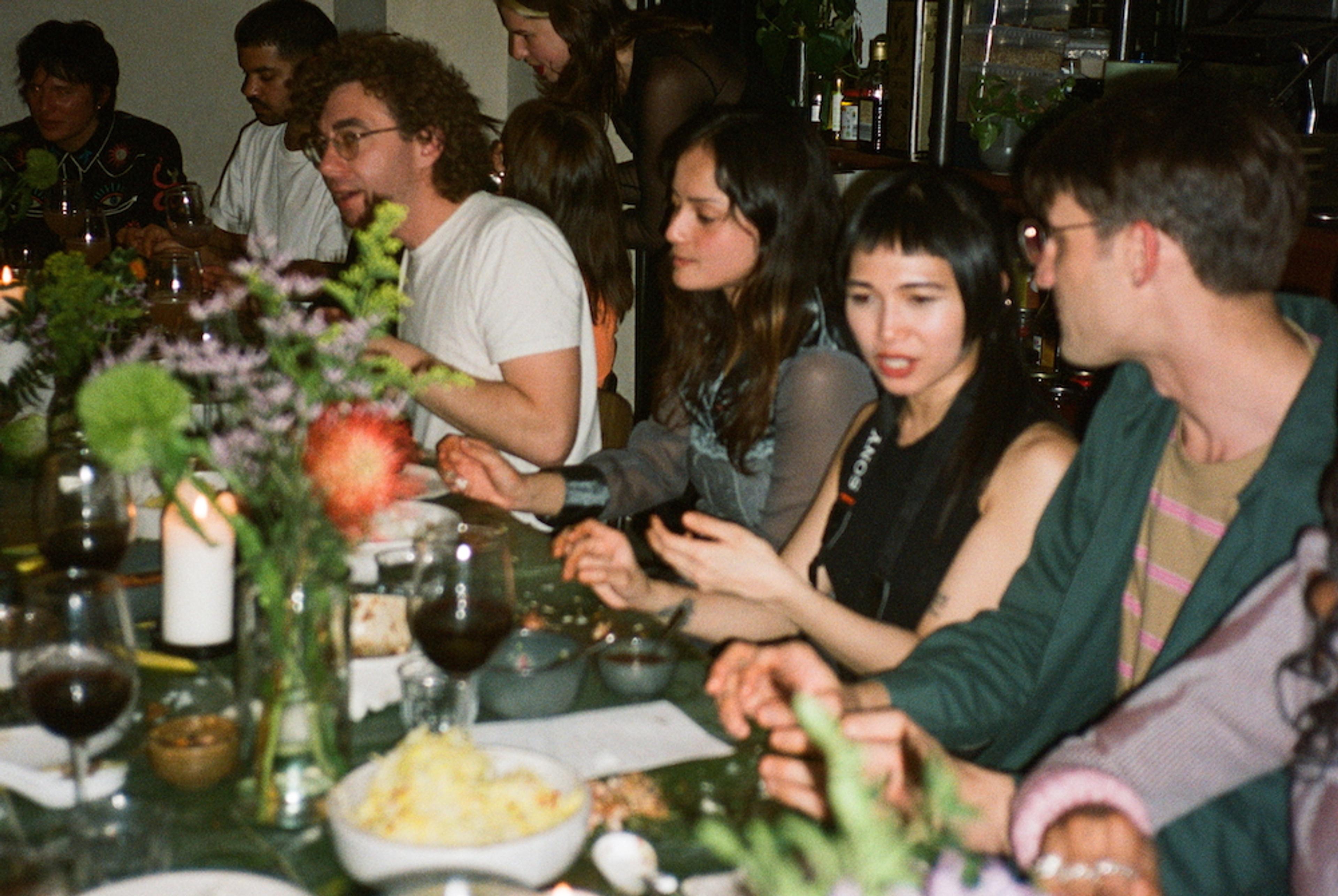 A diverse group of people sitting at the dinner table and are engaged in conversation.