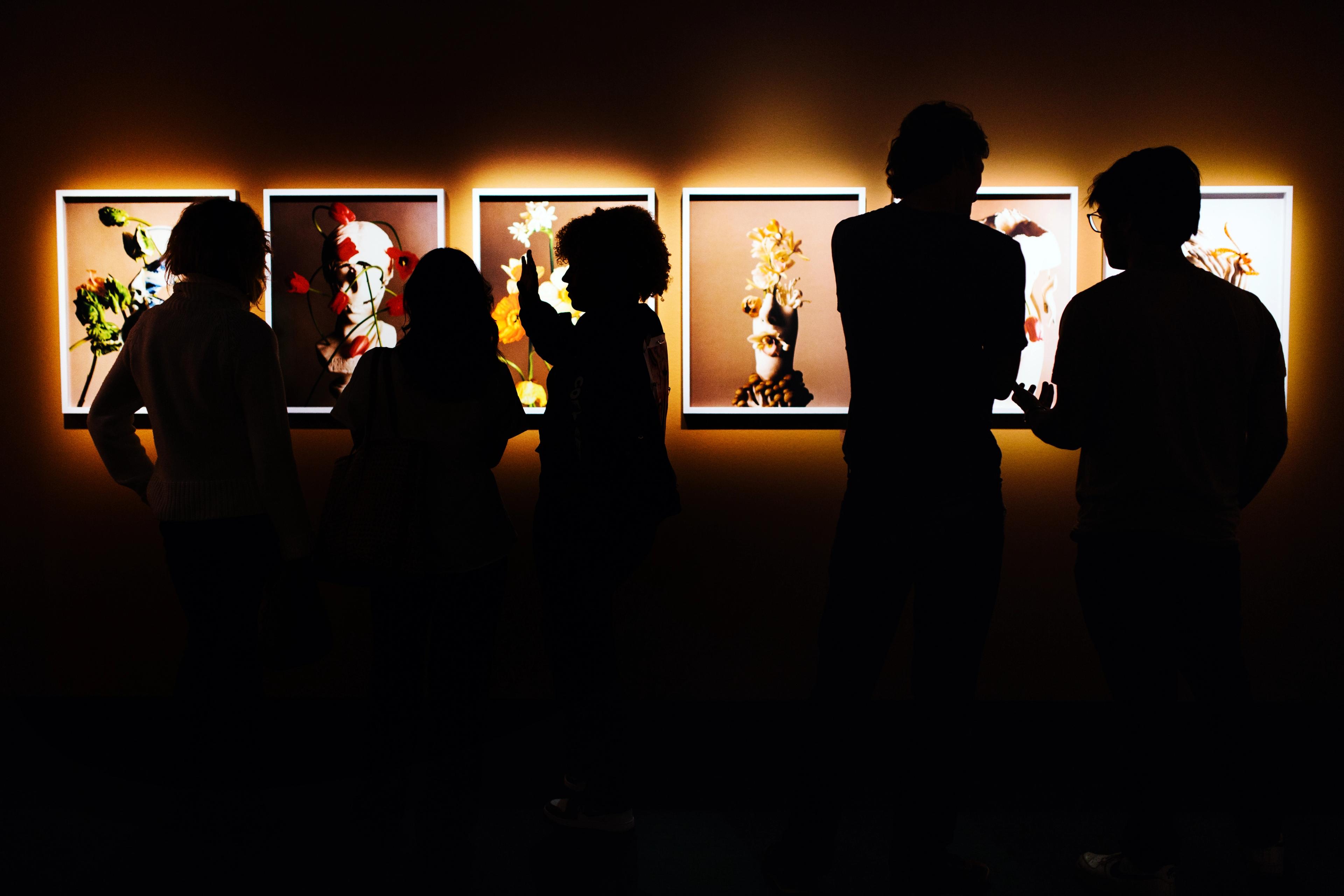 five guests in exhibition hall, photographs on wall