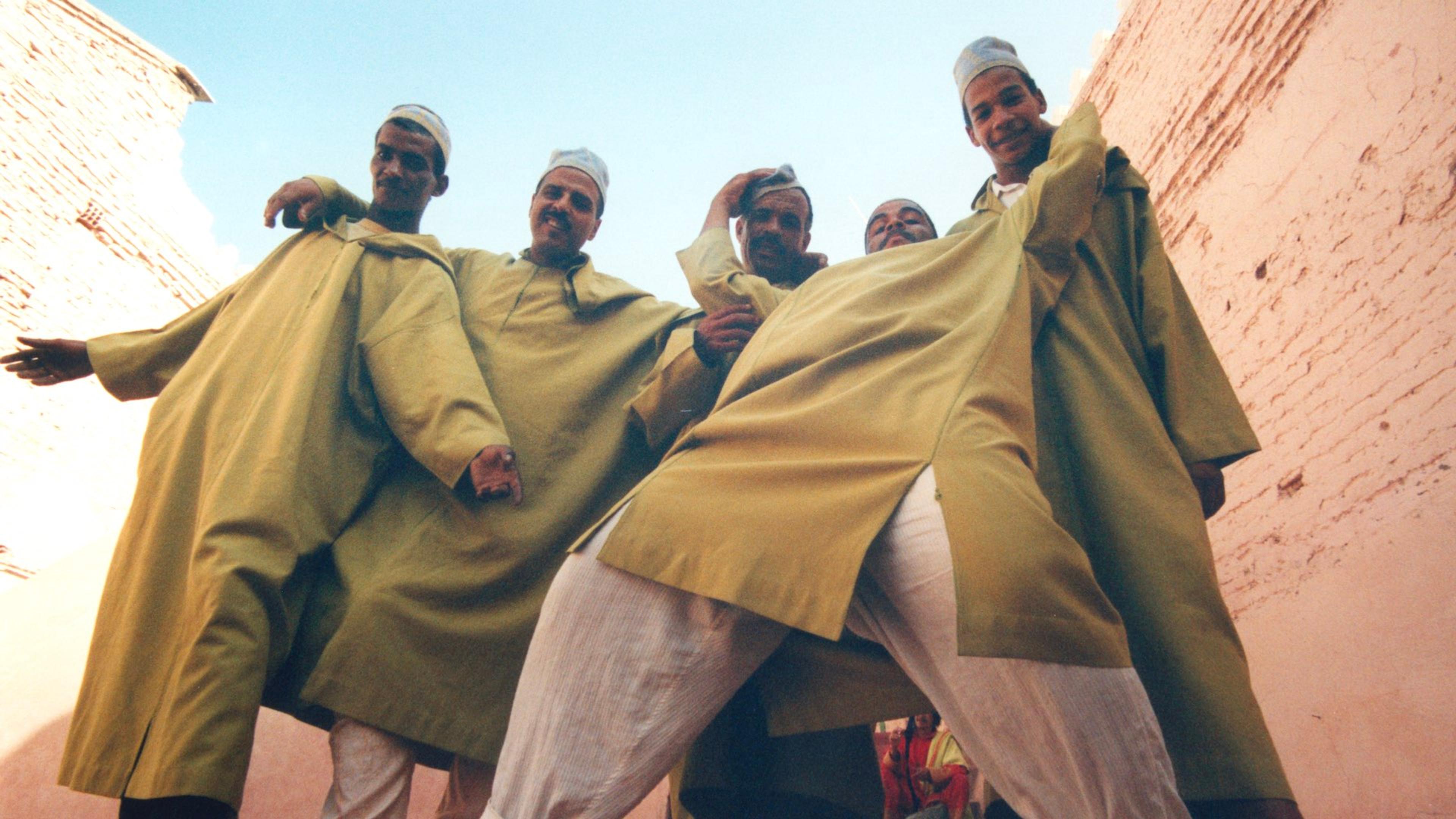 A photograph of a group of men wearing green djellabas and head coverings posing together