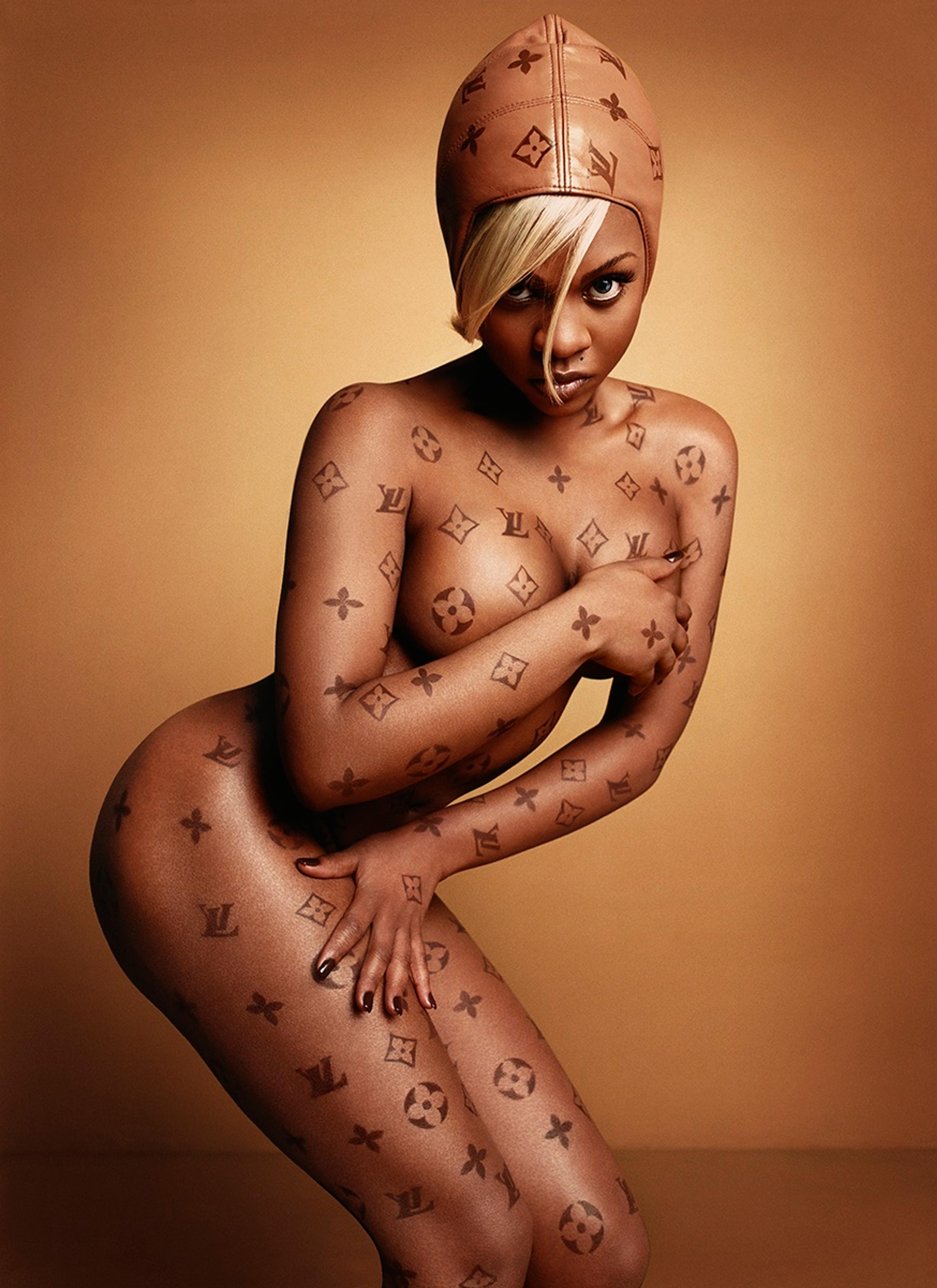 A photograph of a nude woman covered in Louis Vuitton logomarks
