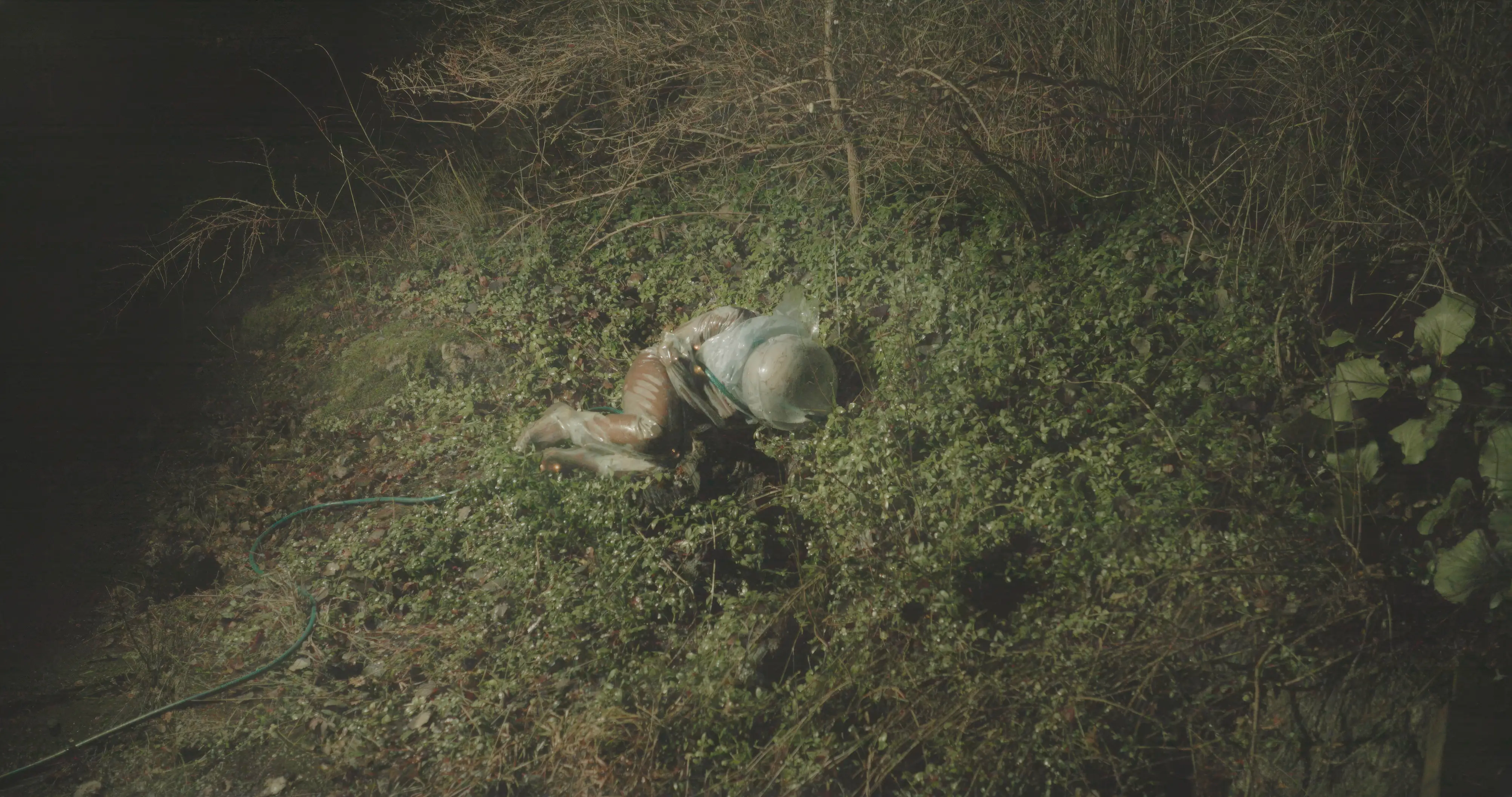 person in a water suit lying down in grass