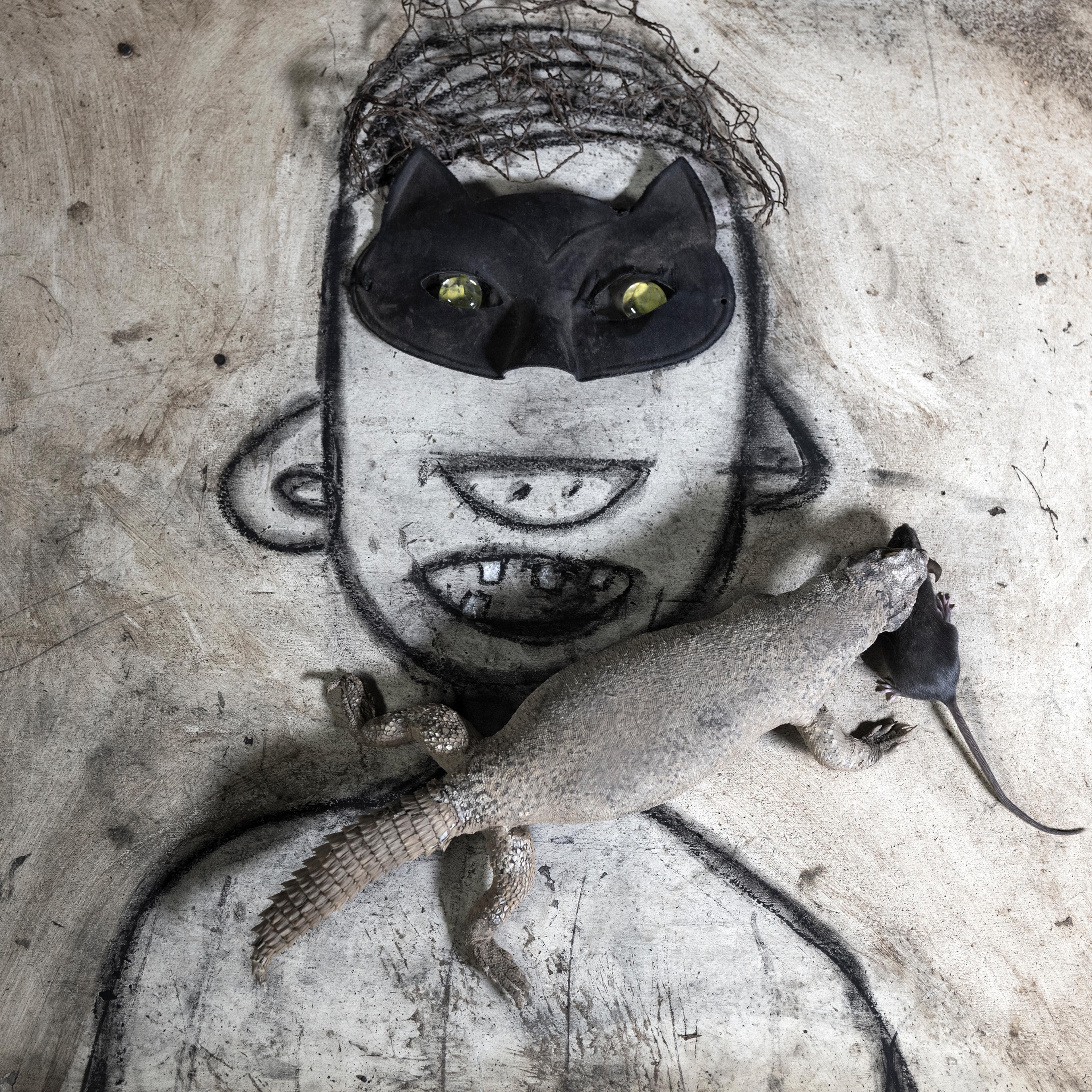 Flor drawing of an upper body with head and kitten mask. On top a alligator with a rat in its mouth