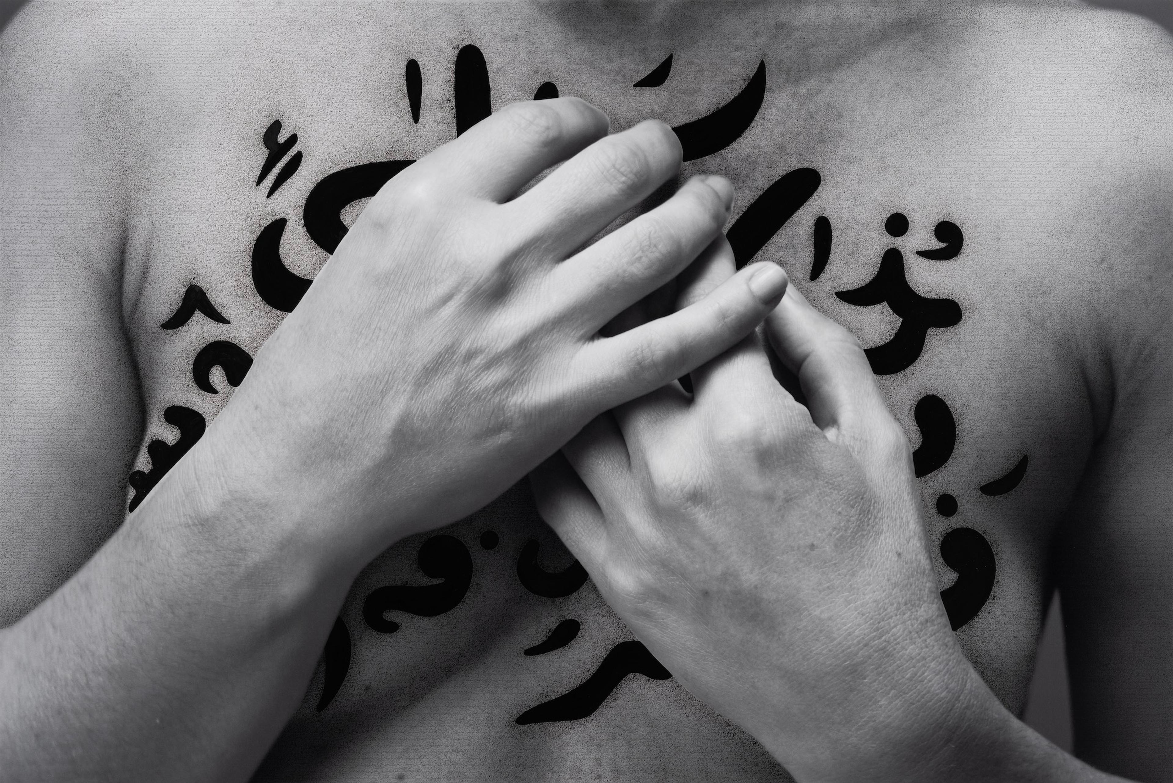 Ein nackter Körper mit zwei Händen auf der Brust, bedeckt mit arabischen Texten.
