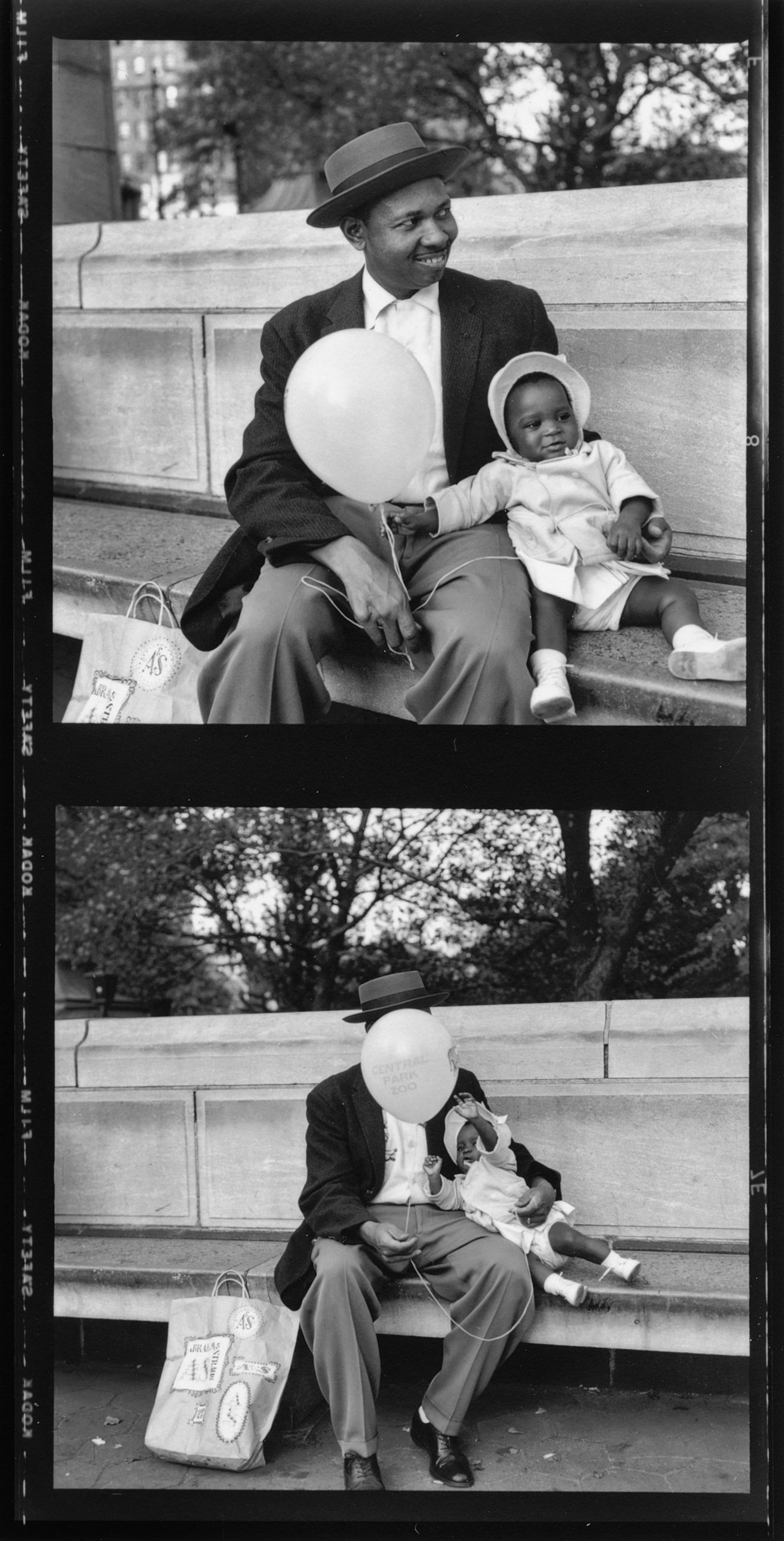 A photograph of a man sitting on a public bench with his baby, holding a balloon