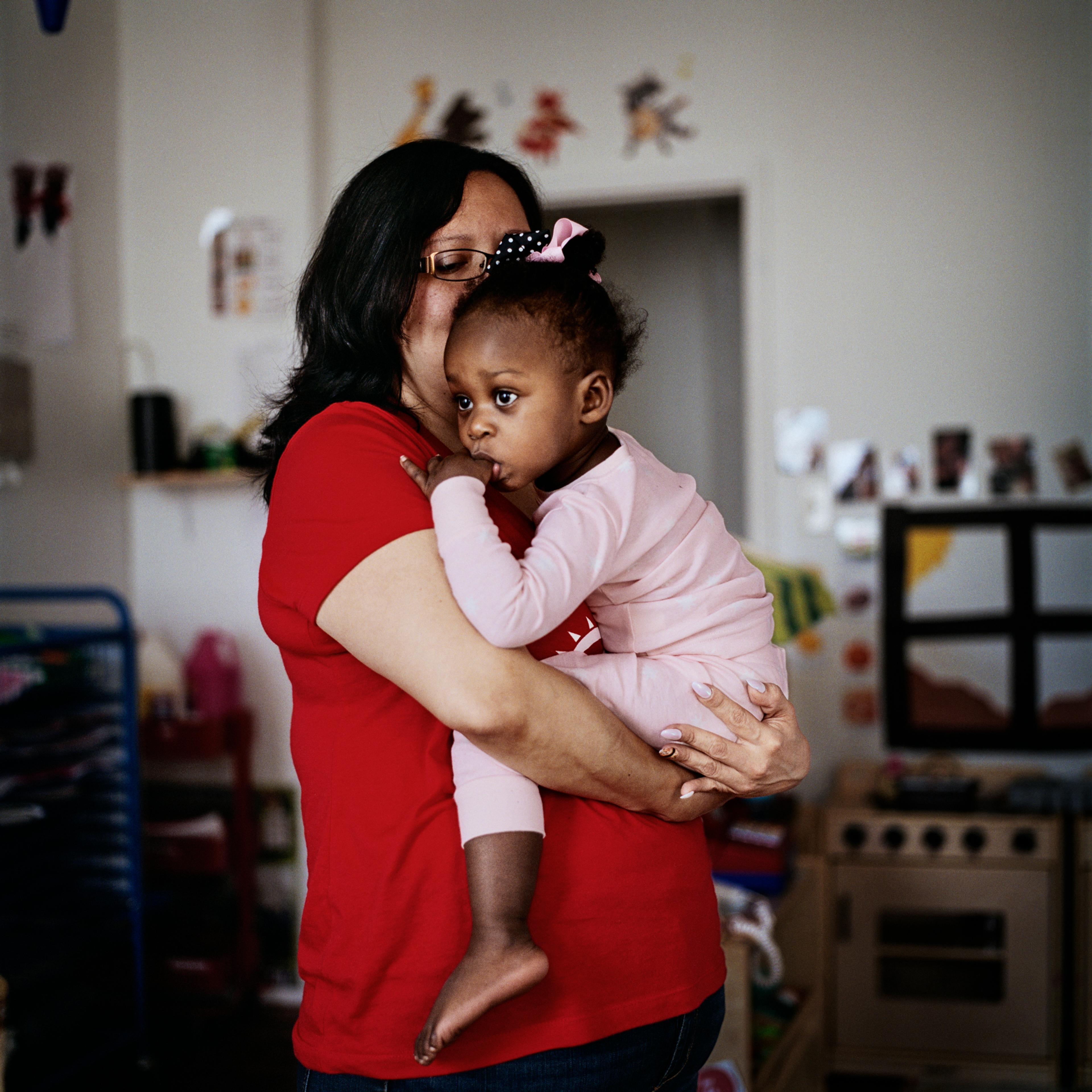 A photograph of a female caretaker and child sharing a hug