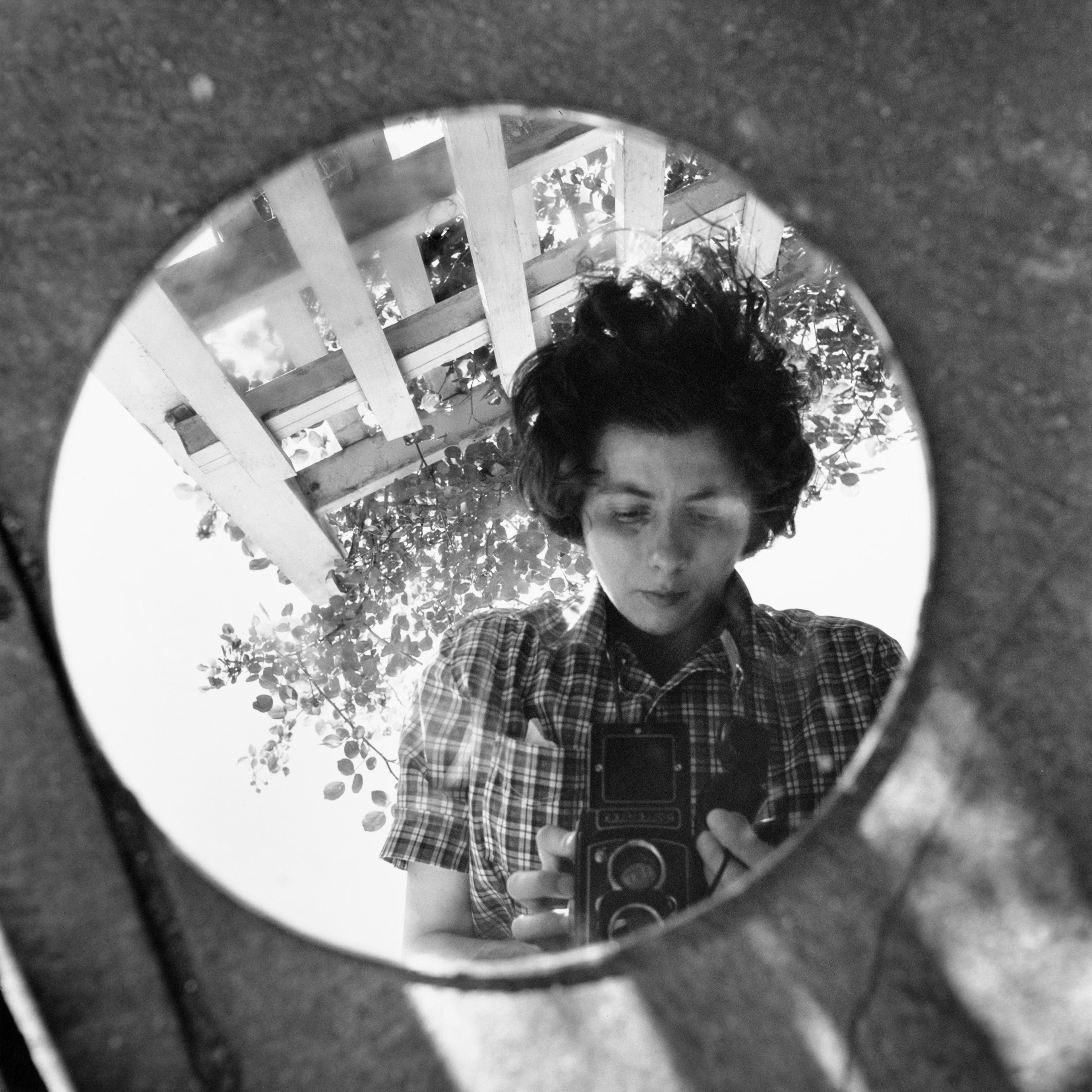 A self portrait of Vivian Maier taken in the reflection of a circular mirror