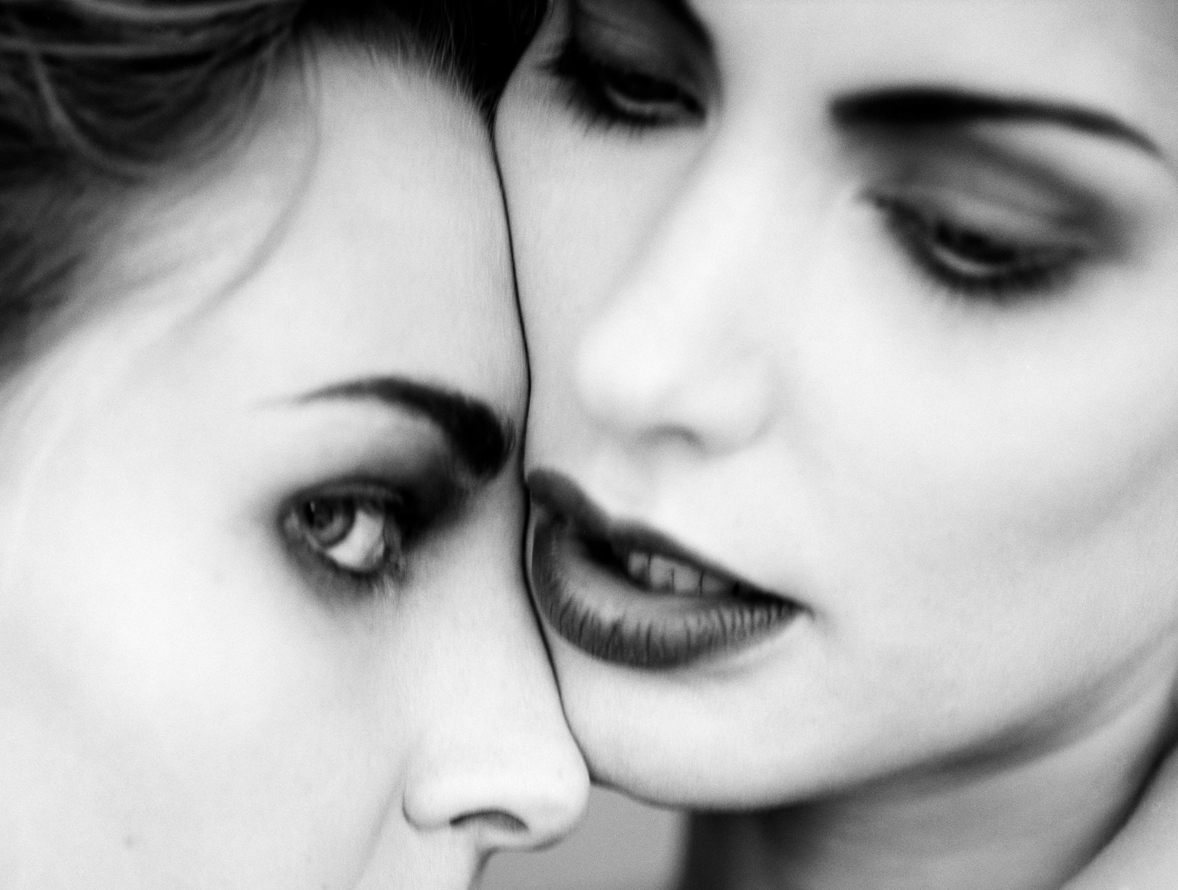 Close-up of two women, one leaning closely toward the other while gazing into the camera.