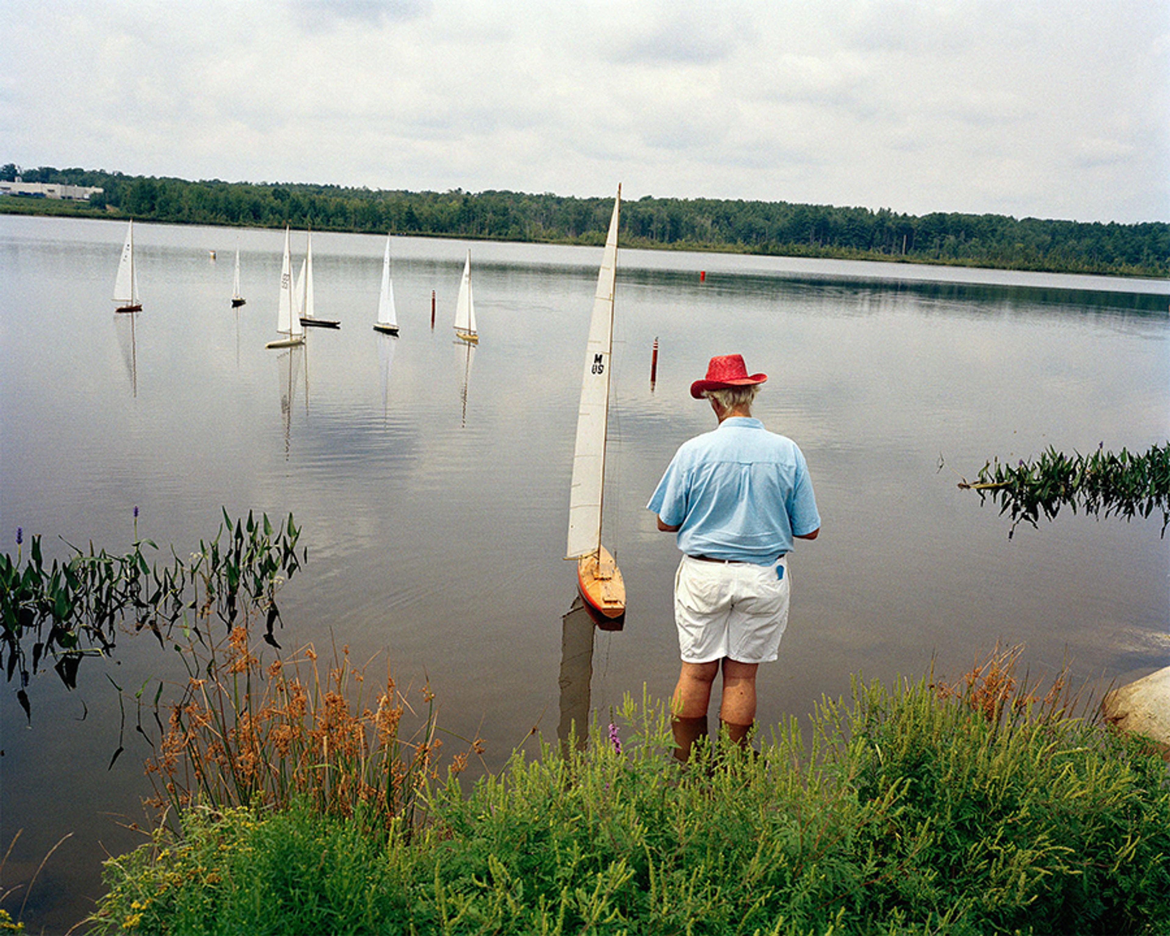Photo by © Sage Sohier, Perfectible Worlds, 2003, man plays with boats on a lake