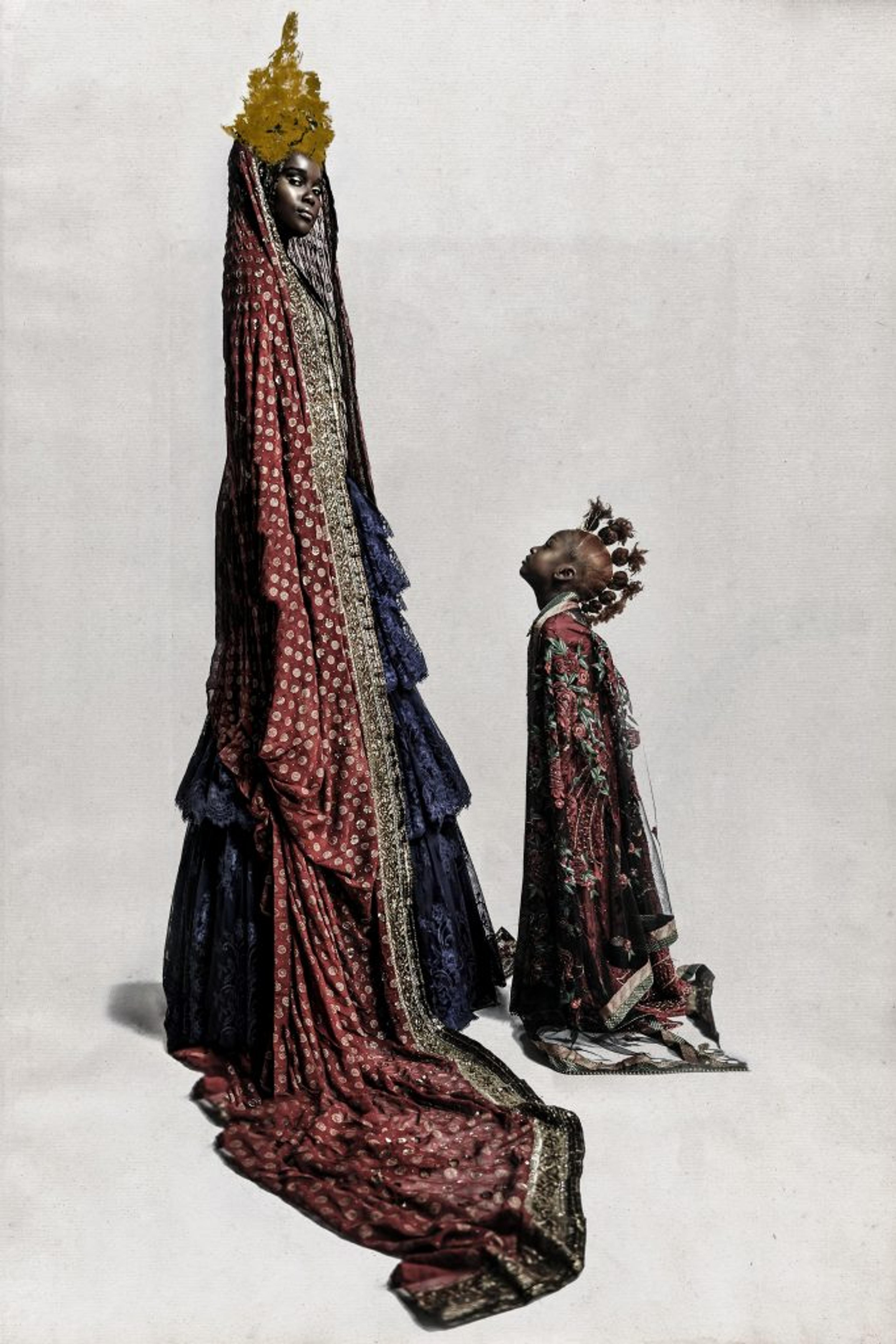 A photograph of a child looking up at an adult wearing a crown and long, flowing garments
