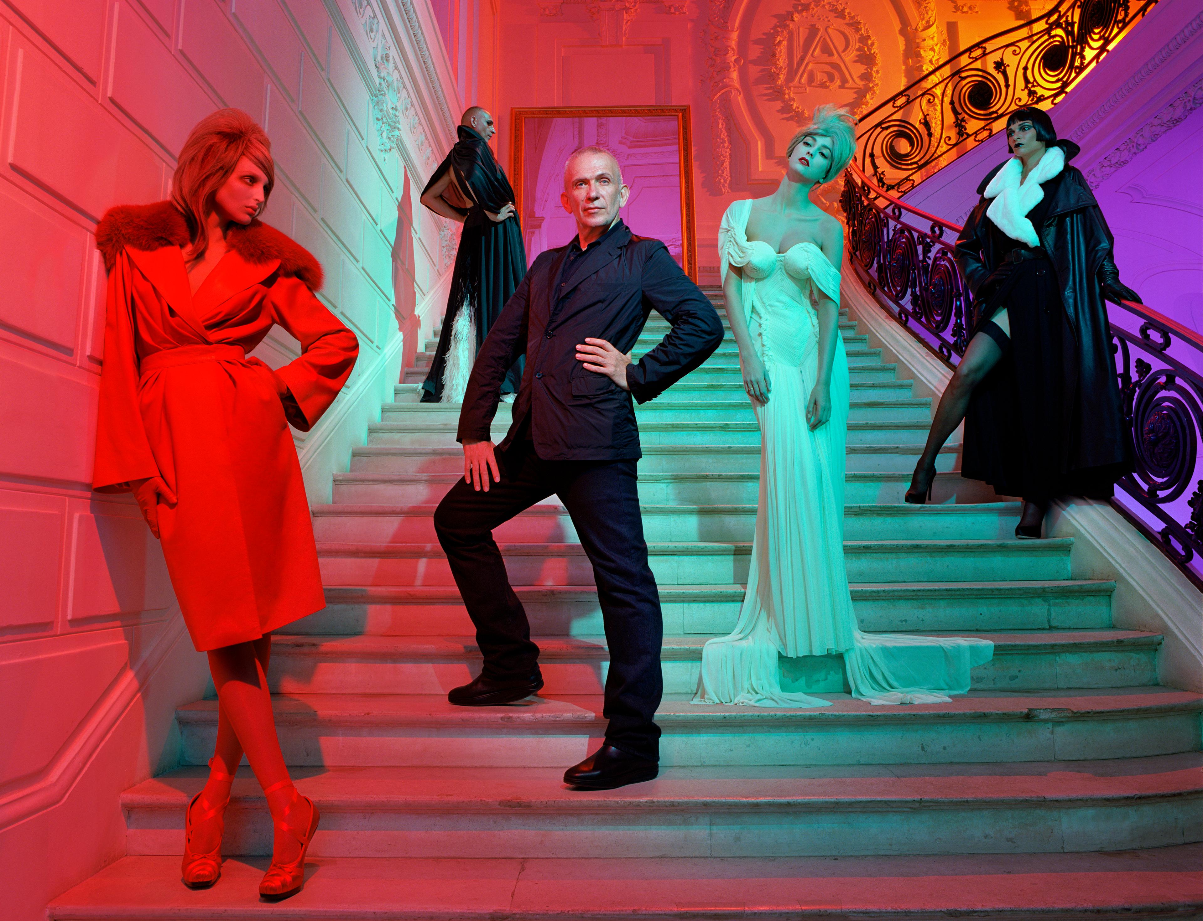 Jean Paul Gaultier standing in the middle surrounded by people wearing designer clothes.
