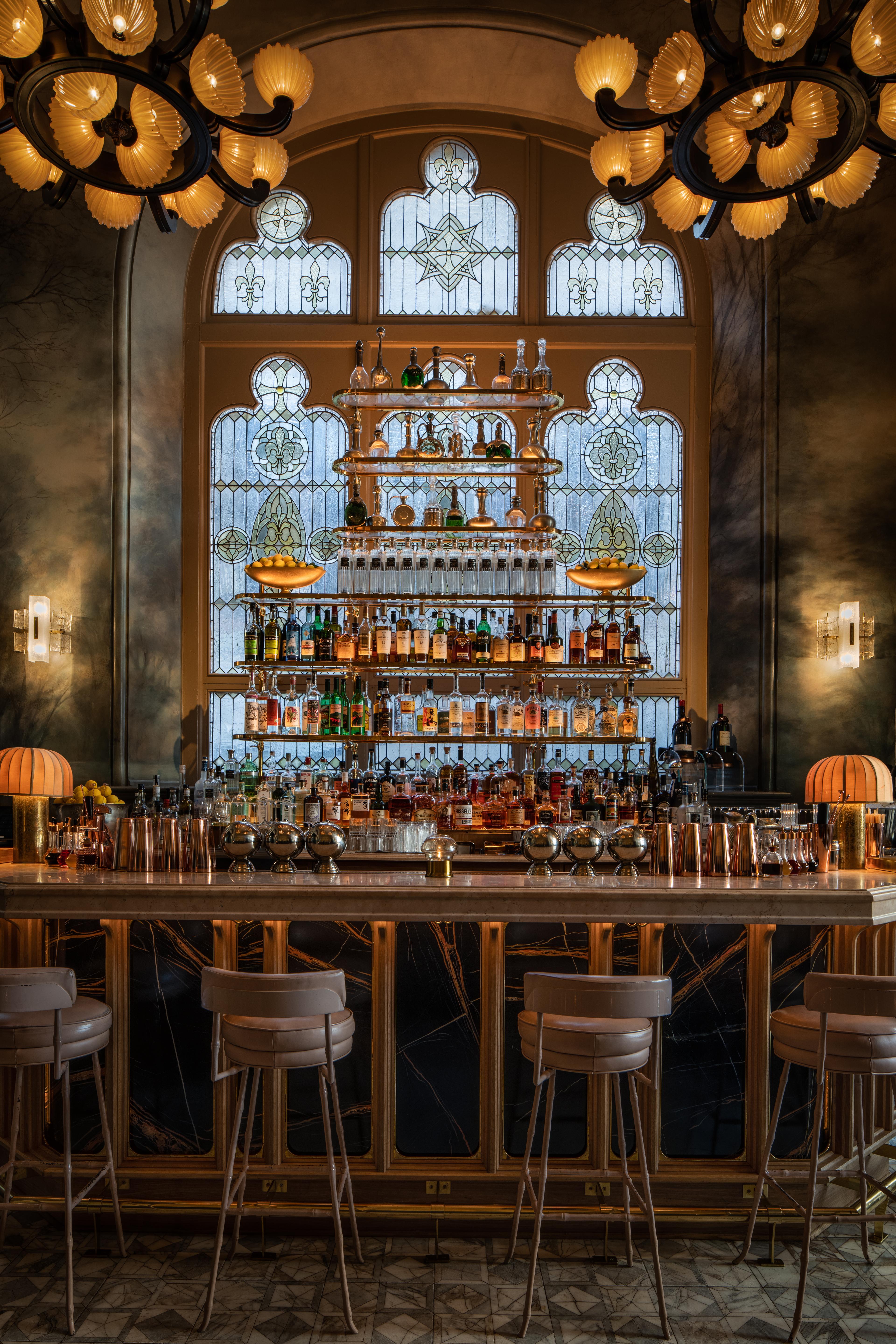 A view of a full bar with opulent chandeliers at a light glow.