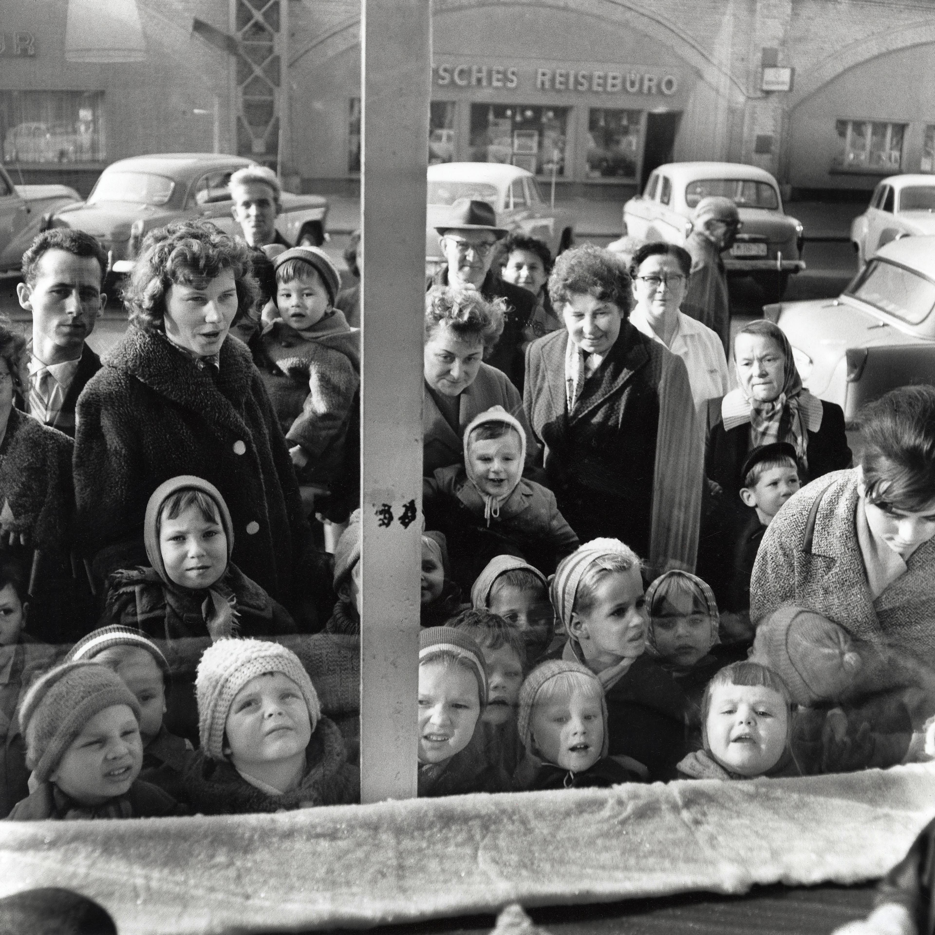 Gruppe von Kindern und Erwachsenen die in ein Schaufenster sehen