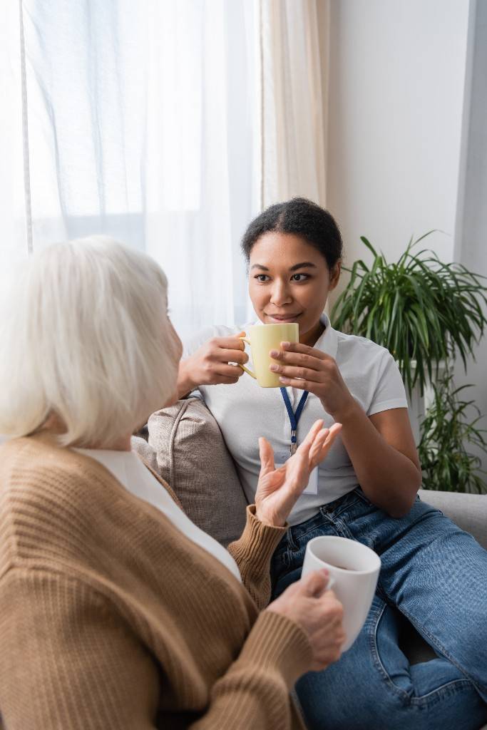Social worker sharing tea and conversation with an older client
