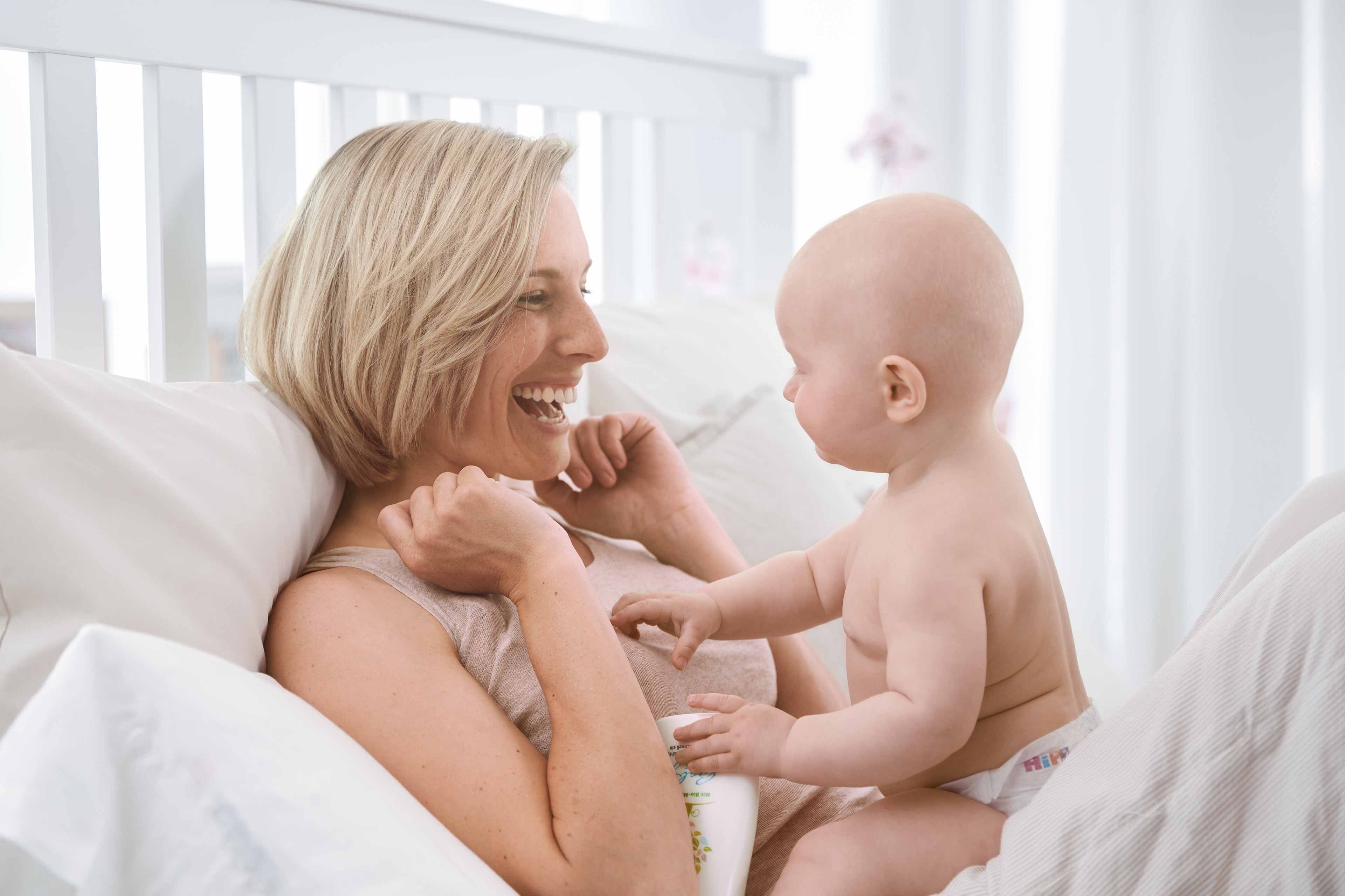 Ein freudiger Moment zwischen einer Frau und einem Baby, wobei die Frau lacht und das Baby sie anschaut.