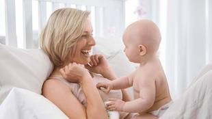 Ein freudiger Moment zwischen einer Frau und einem Baby, wobei die Frau lacht und das Baby sie anschaut.