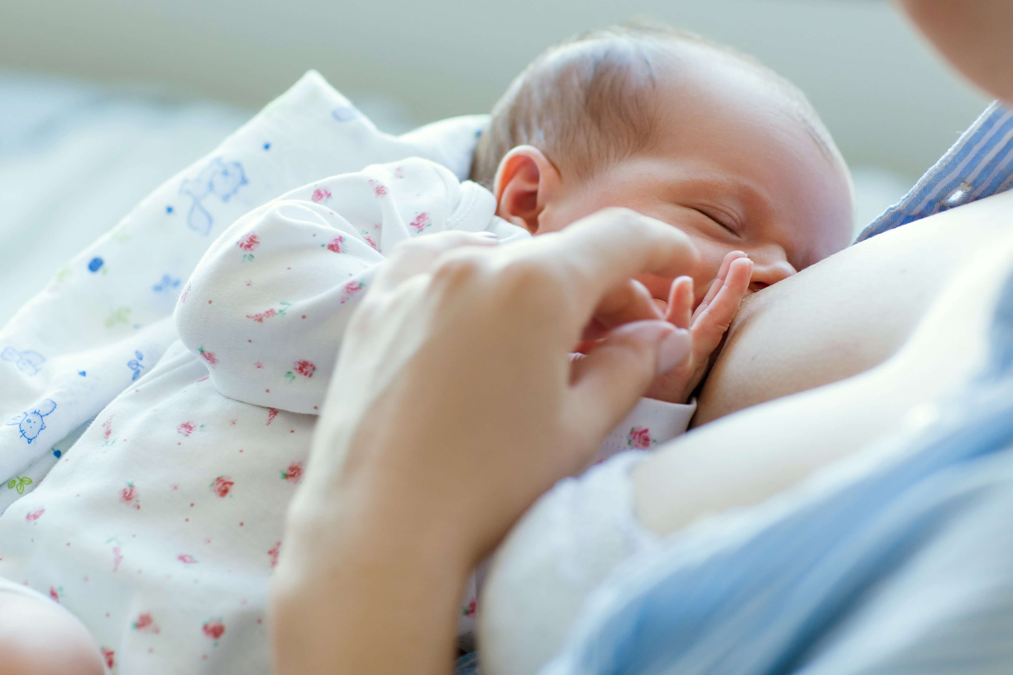 Ein zarter Moment, in dem ein Baby von einem Elternteil sanft gehalten und gestillt wird.