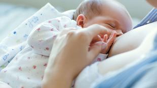 Ein zarter Moment, in dem ein Baby von einem Elternteil sanft gehalten und gestillt wird.