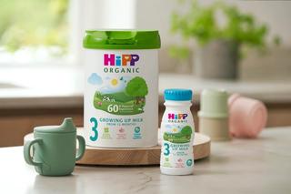 HiPP Organic growing up milk powder and ready to feed next to a sippy cup on a kitchen worktop