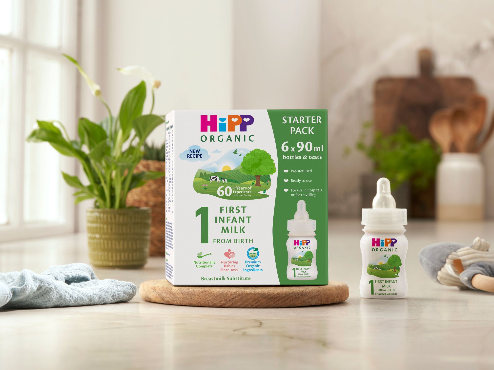 HiPP Organic ready to feed infant starter pack next to a bottle of milk on a kitchen worktop