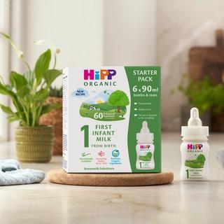 HiPP Organic ready to feed infant starter pack next to a bottle of milk on a kitchen worktop
