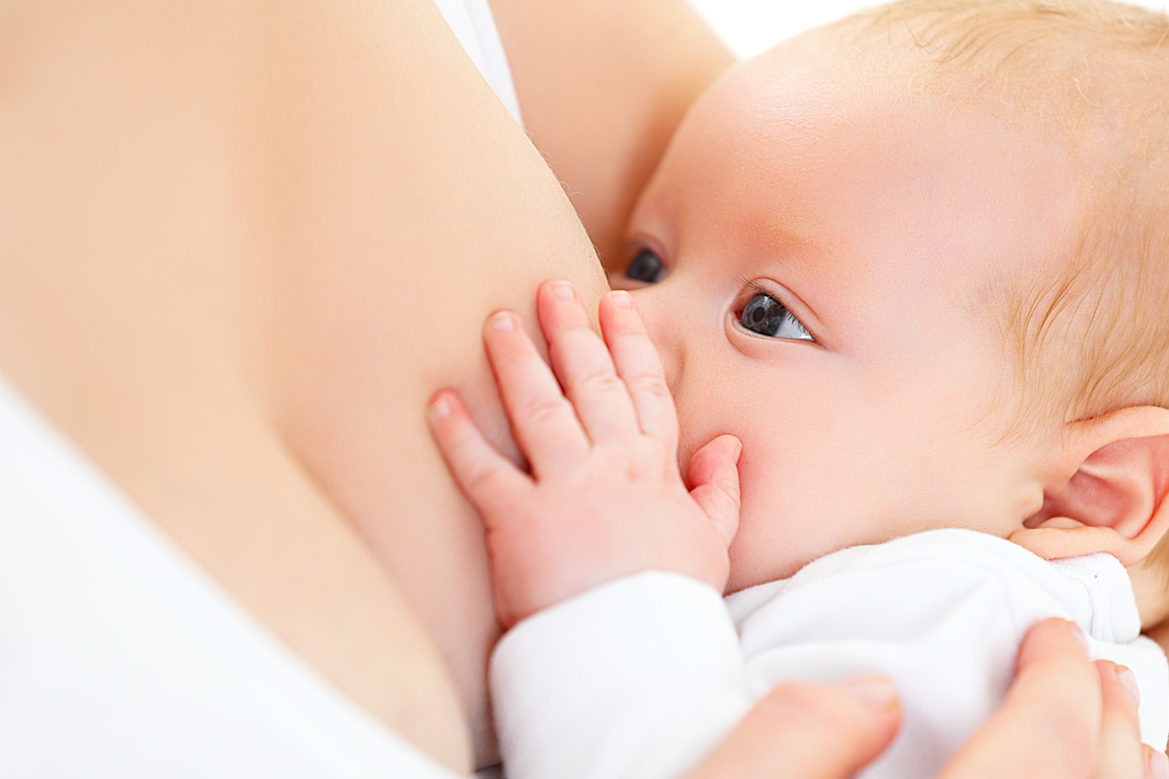 Ein Baby, das seine Hand auf die Brust der Mutter legt und zu säugen scheint.