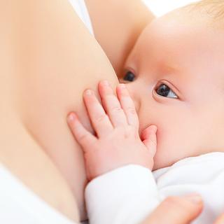 Ein Baby, das seine Hand auf die Brust der Mutter legt und zu säugen scheint.