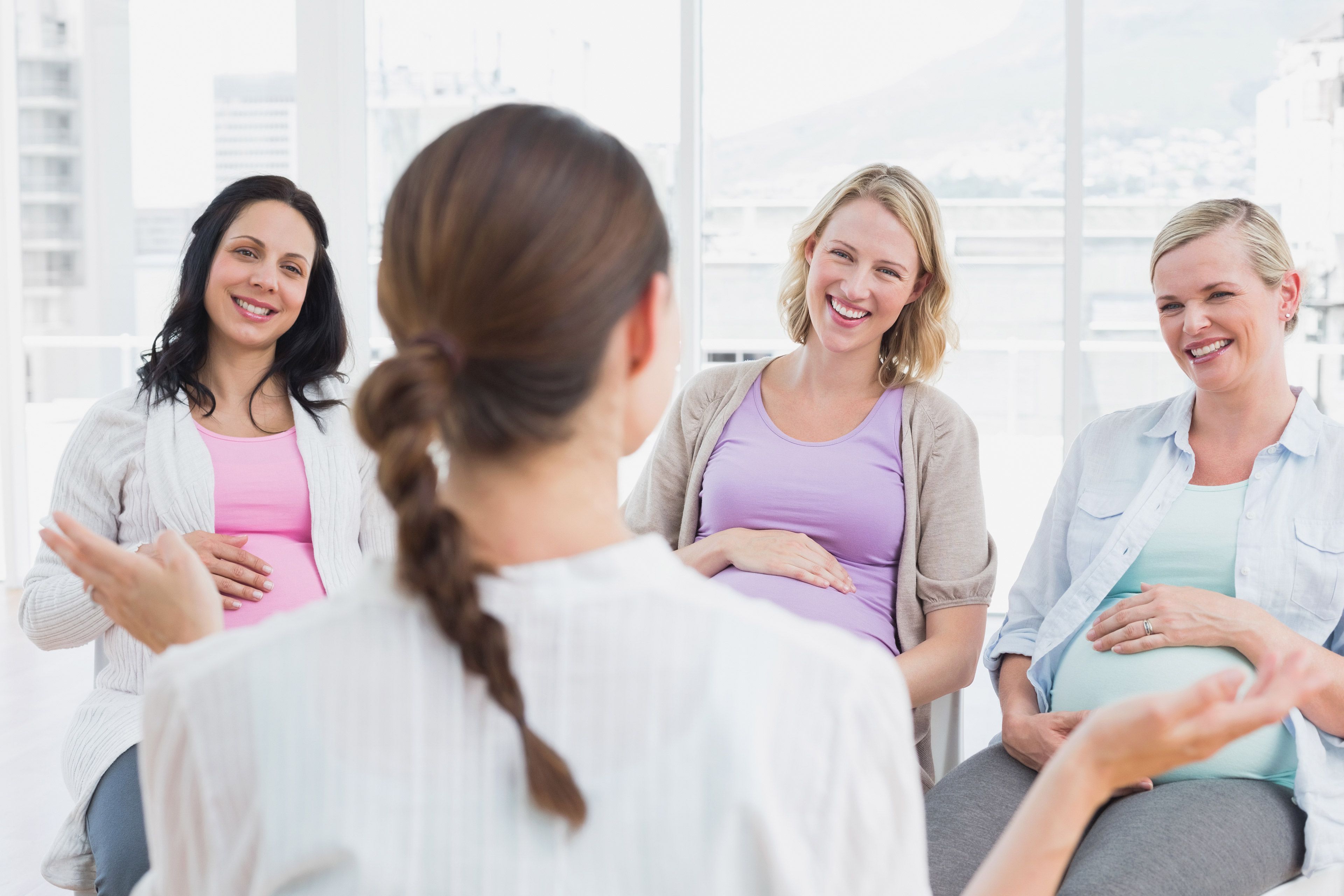 Vier Frauen in einem hellen Raum, in ein Gespräch vertieft.