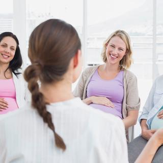 Vier Frauen in einem hellen Raum, in ein Gespräch vertieft.