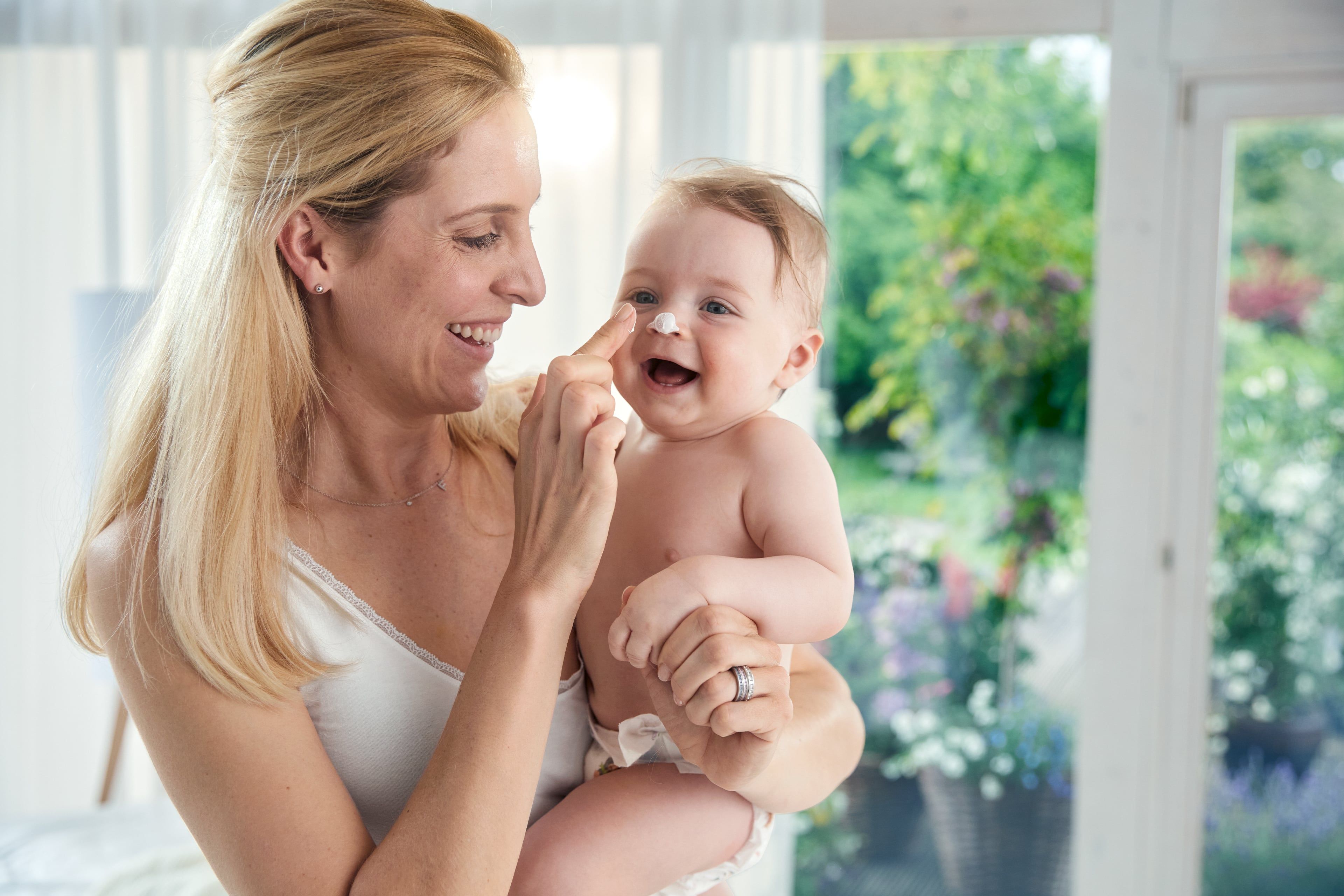 Ein zärtlicher Moment zwischen einer Mutter und ihrem Baby, in dem die Mutter spielerisch die Nase des Babys berührt.